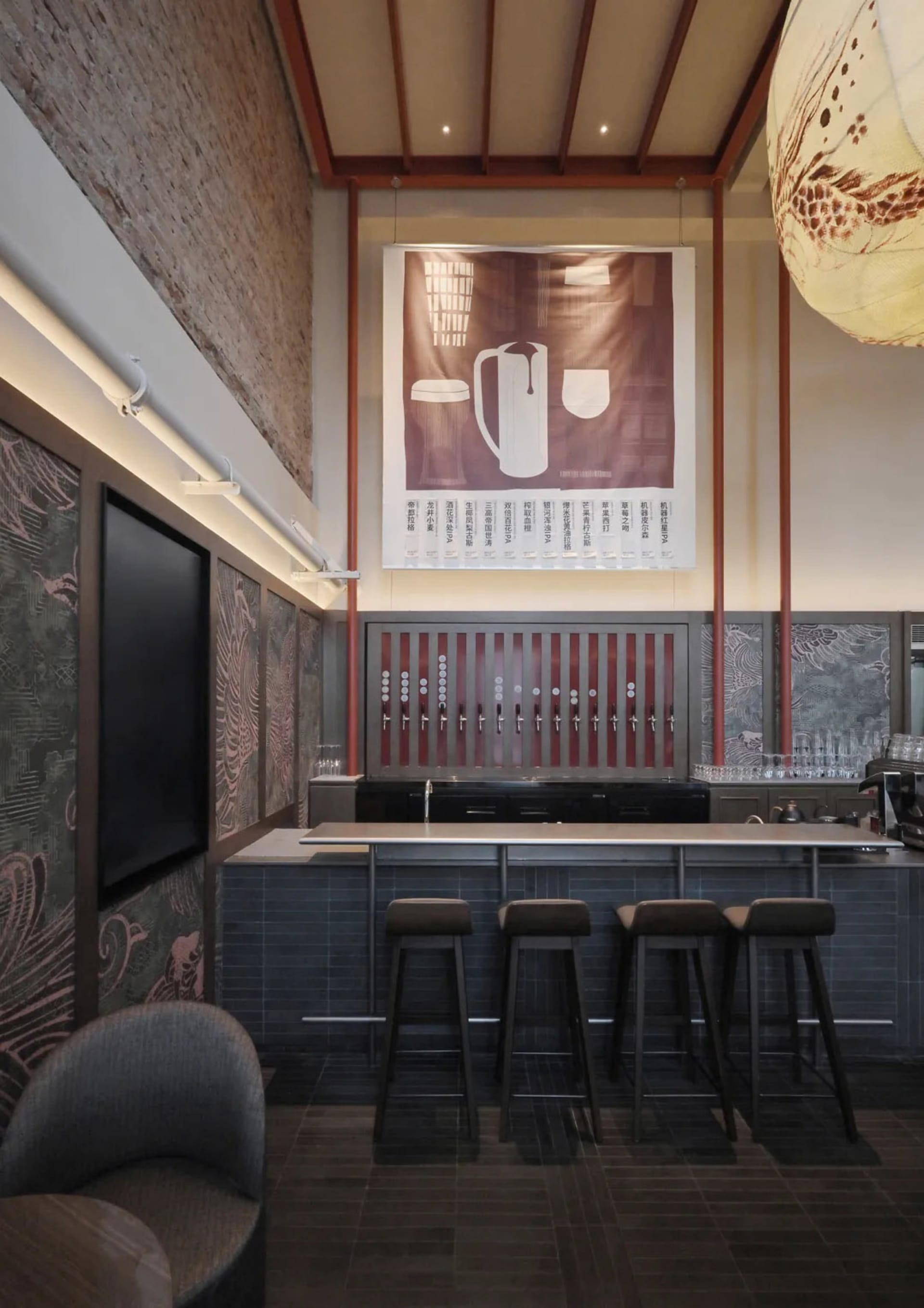 A modern bar with a black counter, brown and white decor, and black stools, featuring a TV on the wall and dim lighting