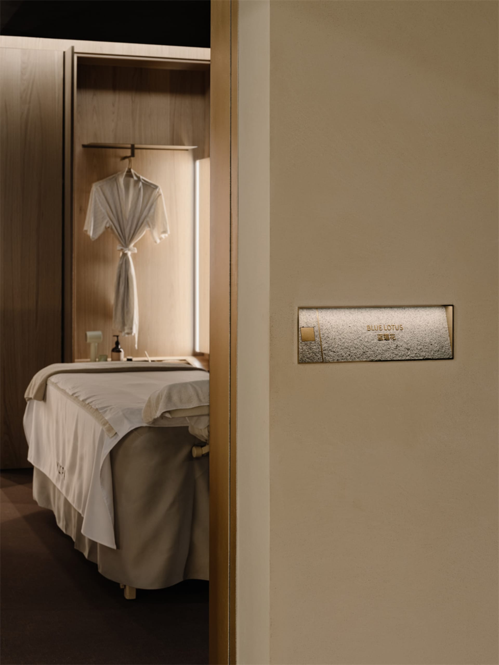 A modern bedroom with a bed against the wall, a closet next to it, and a white sheet covering the bed, in a well-lit space