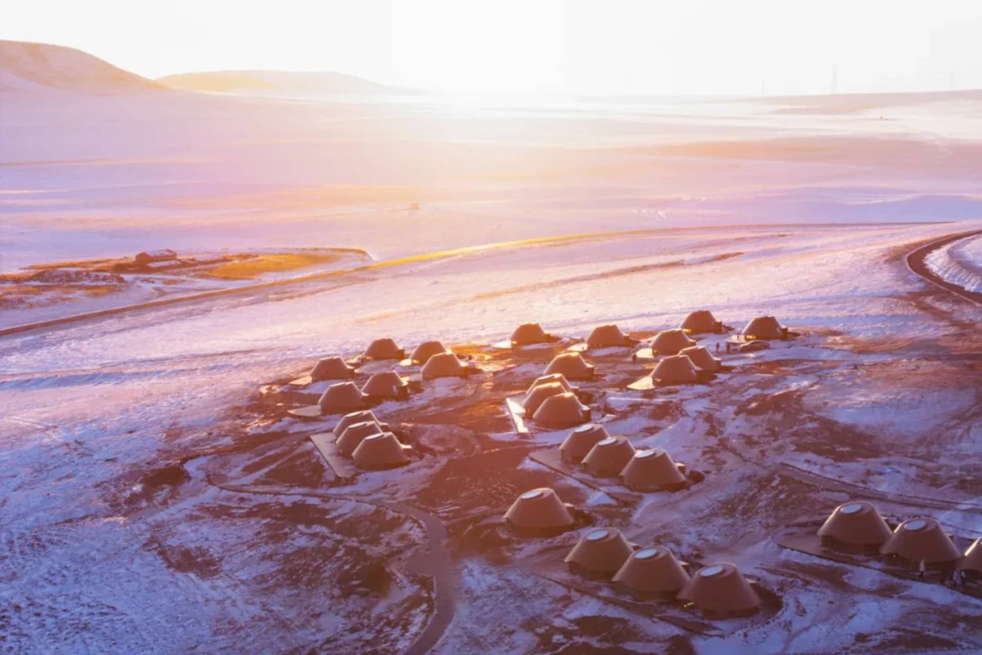 A serene snowy landscape with small, rustic wood cabins surrounded by snow, creating a peaceful atmosphere