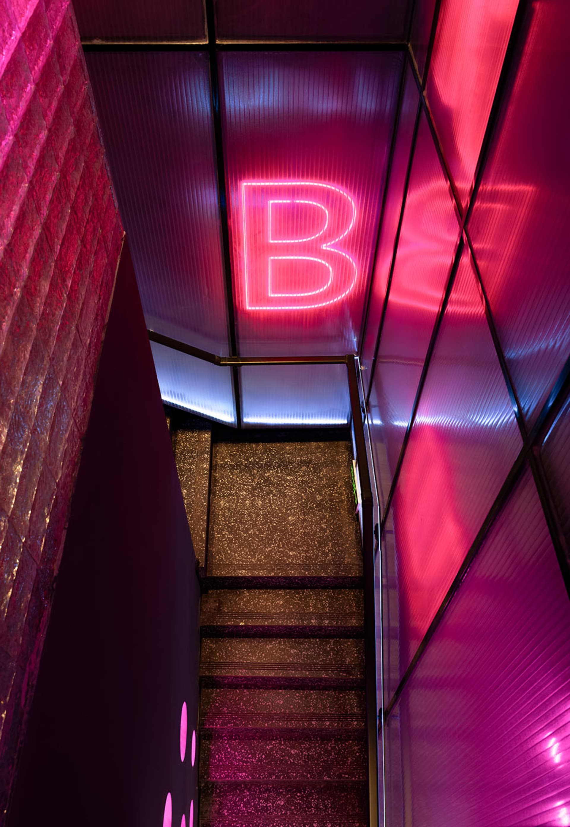 A modern staircase in a hallway with a pink lighting effect, surrounded by a stylish interior setting