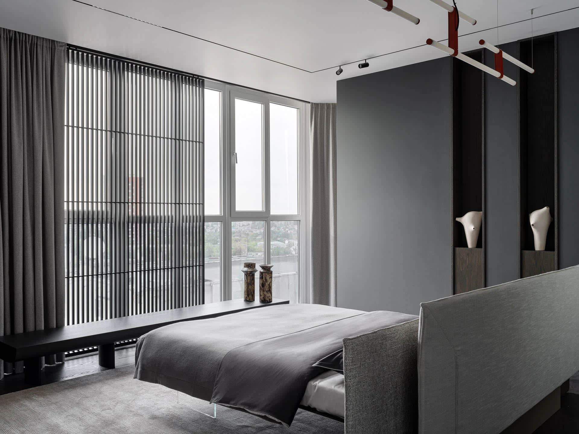 A well-lit bedroom with a bed, chair, and window, featuring predominantly white materials and a modern design