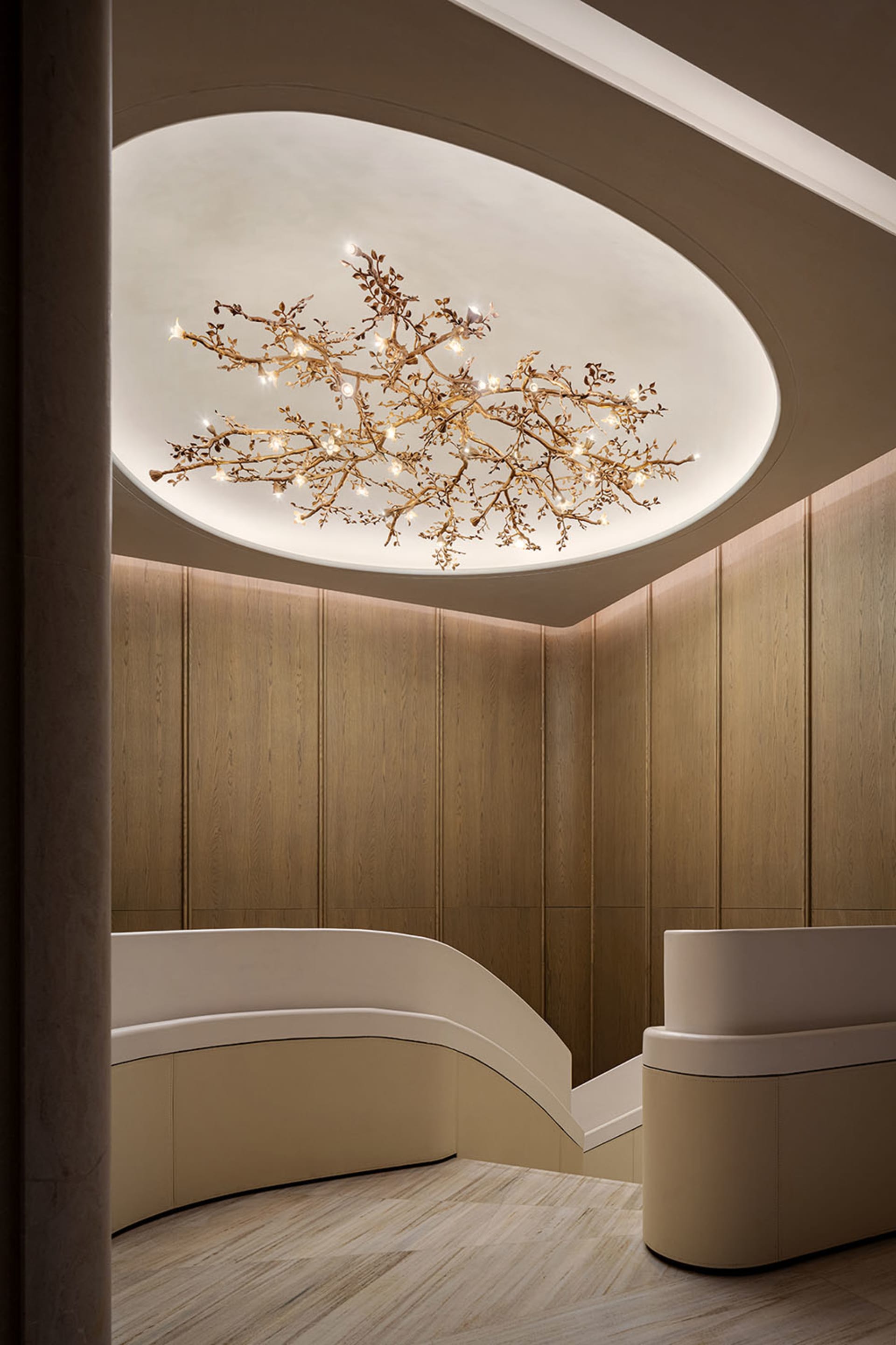 Dimly lit lobby with a wooden ceiling, a large chandelier, and a staircase in the background