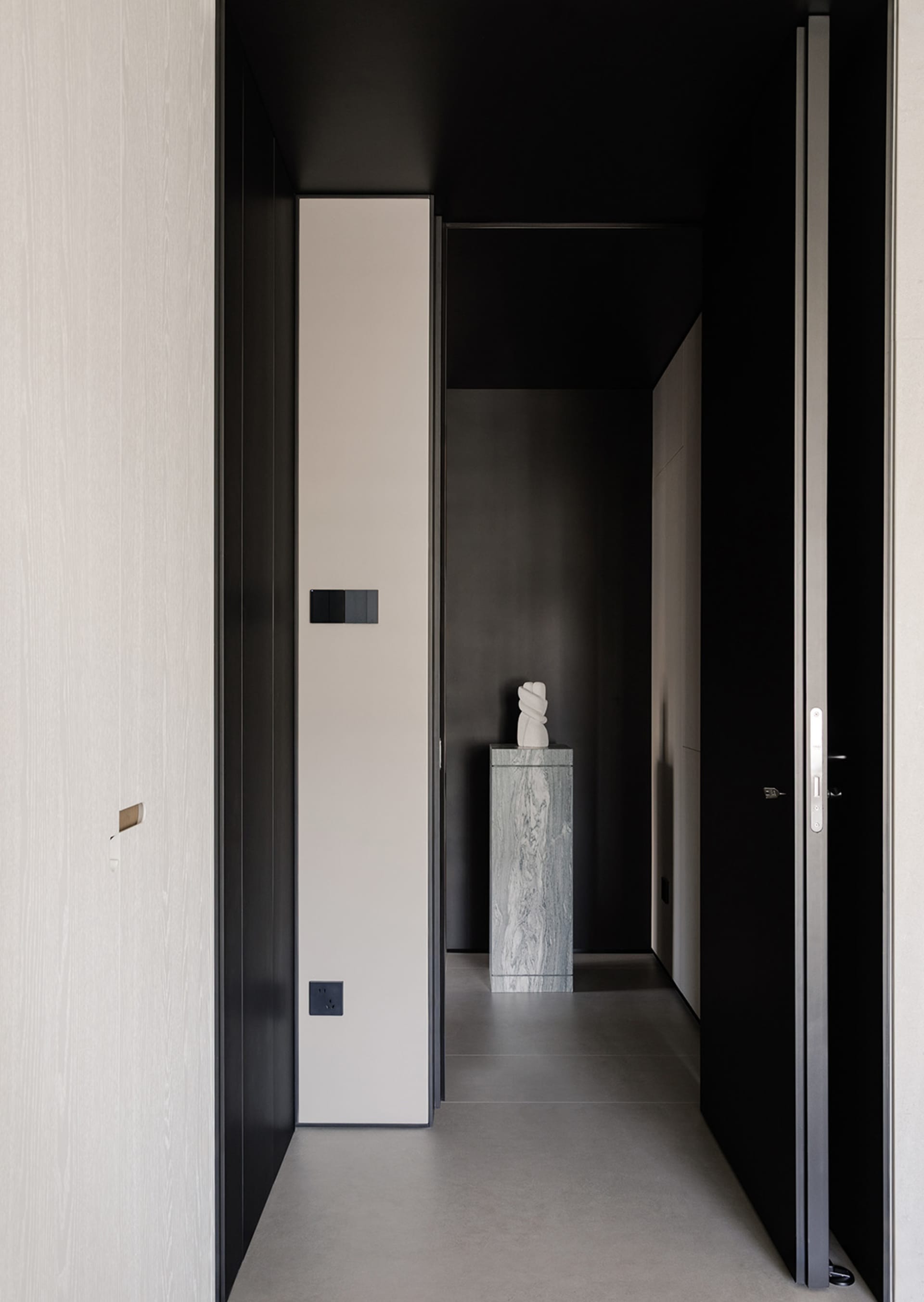 A dark and narrow hallway with wooden walls, a tile floor, and a statue on display, creating a simple and elegant atmosphere