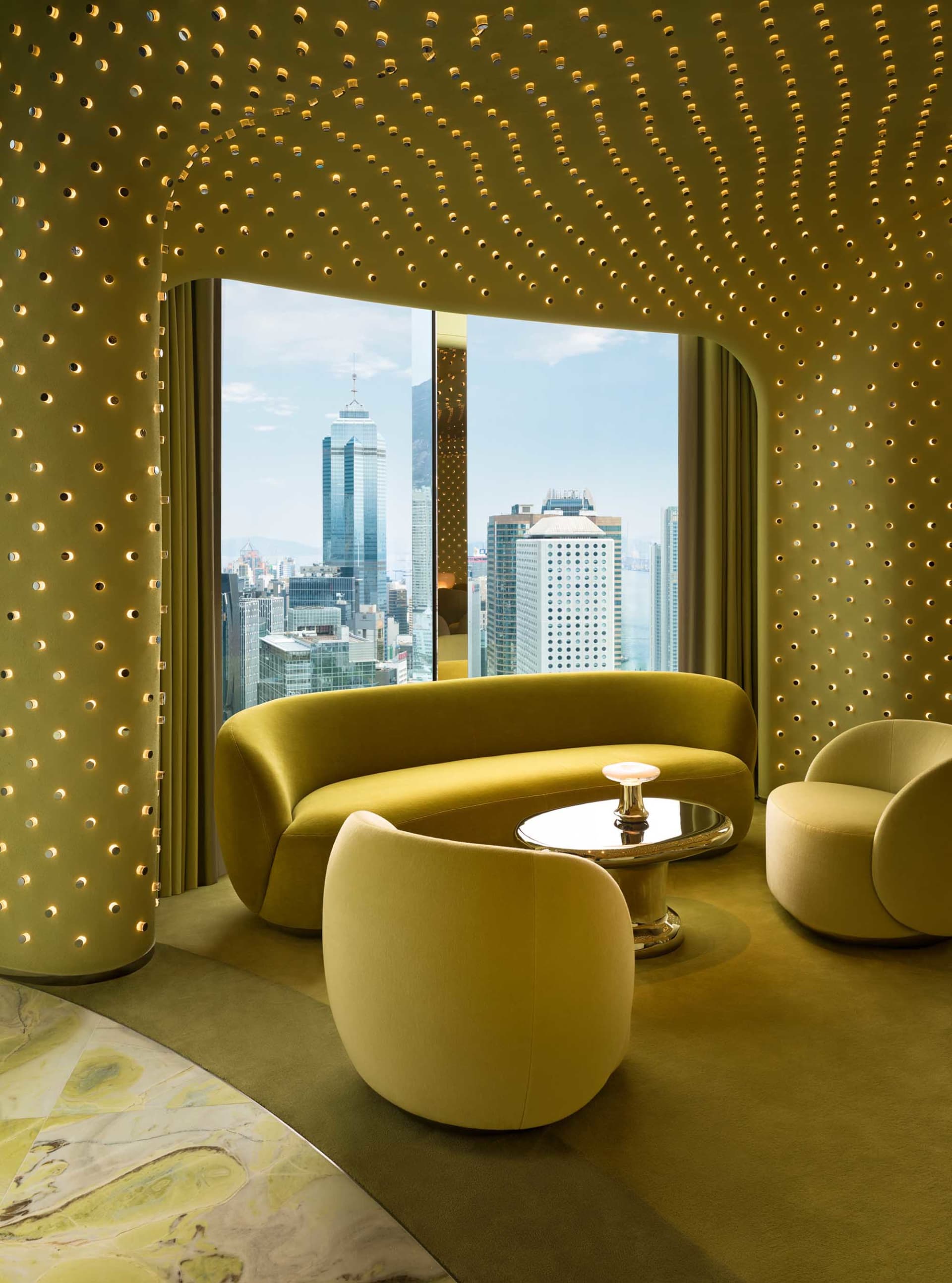 A modern living room with a couch, chair, and dining table, featuring a large window with a city view, yellow and white colors, and bright lighting
