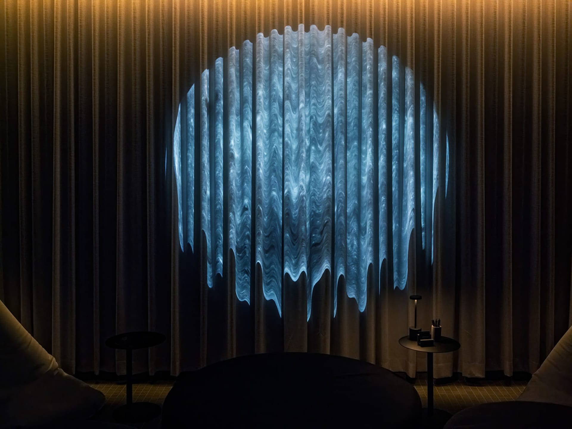 Dimly lit room with a blue patterned curtain, a chair, and a dining table in the background