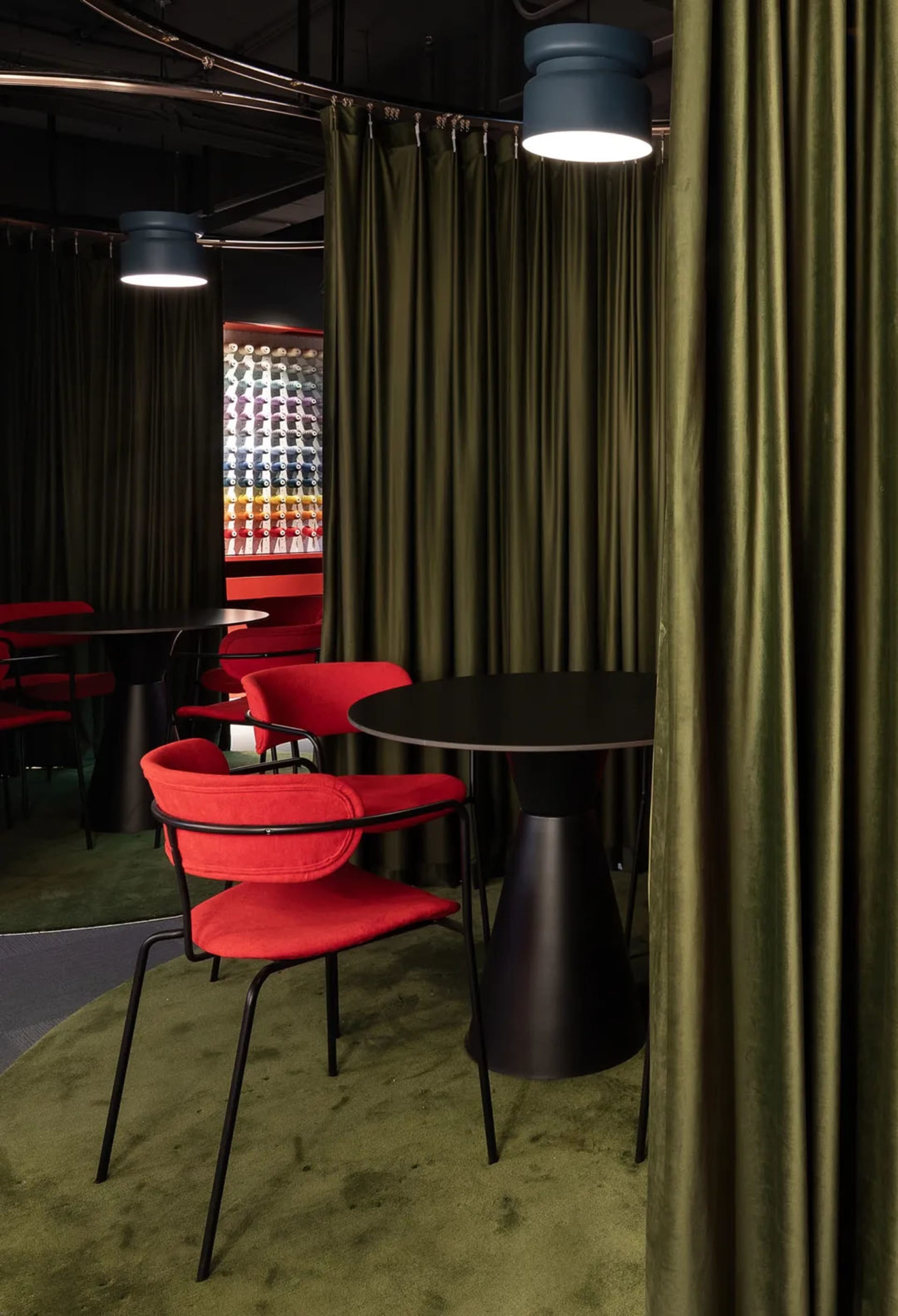 A cozy dining area with a black table surrounded by red chairs and a elegant curtain in the background