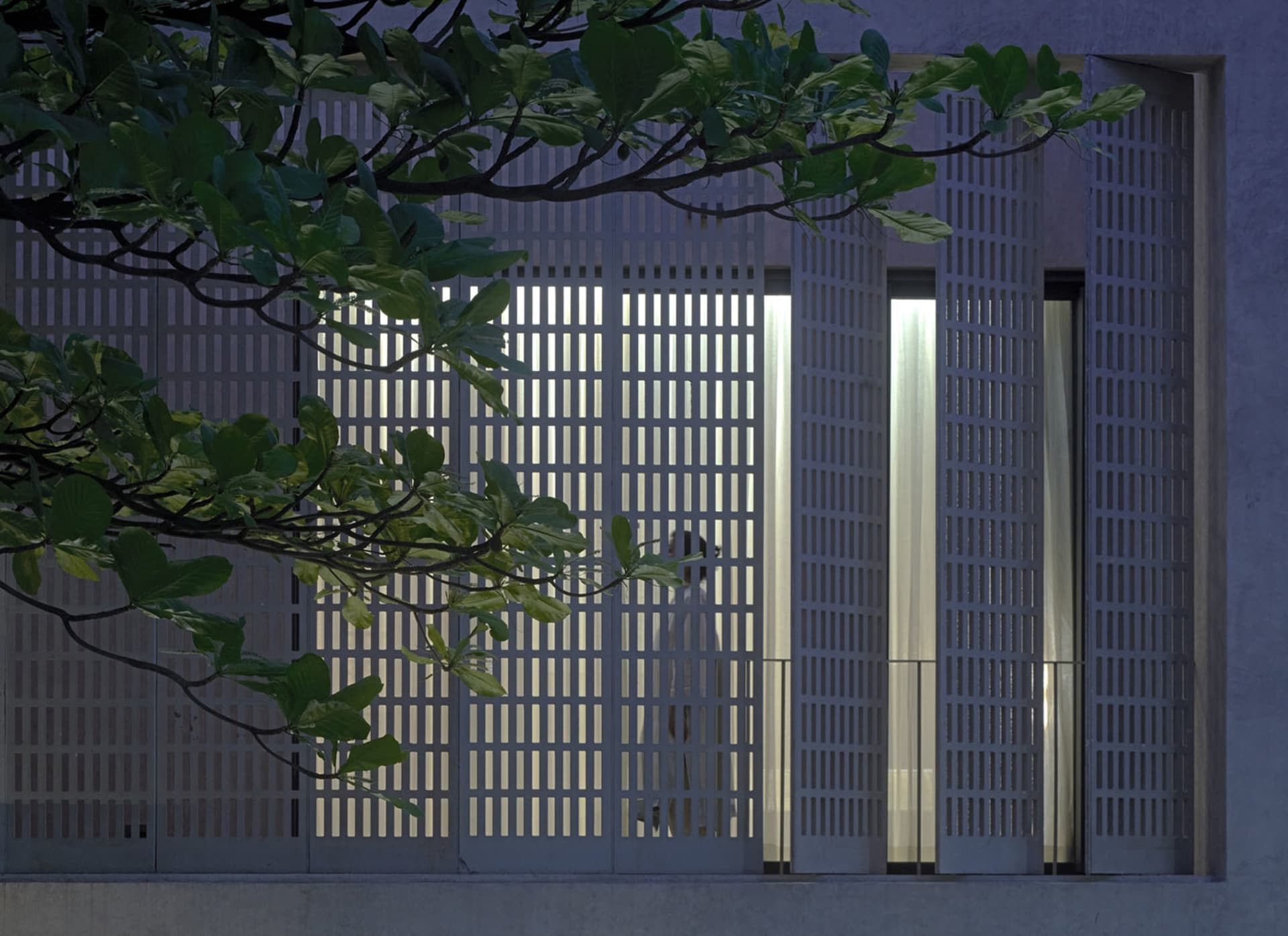 A white dog stands in a window of a modern building, looking out at the scene outside