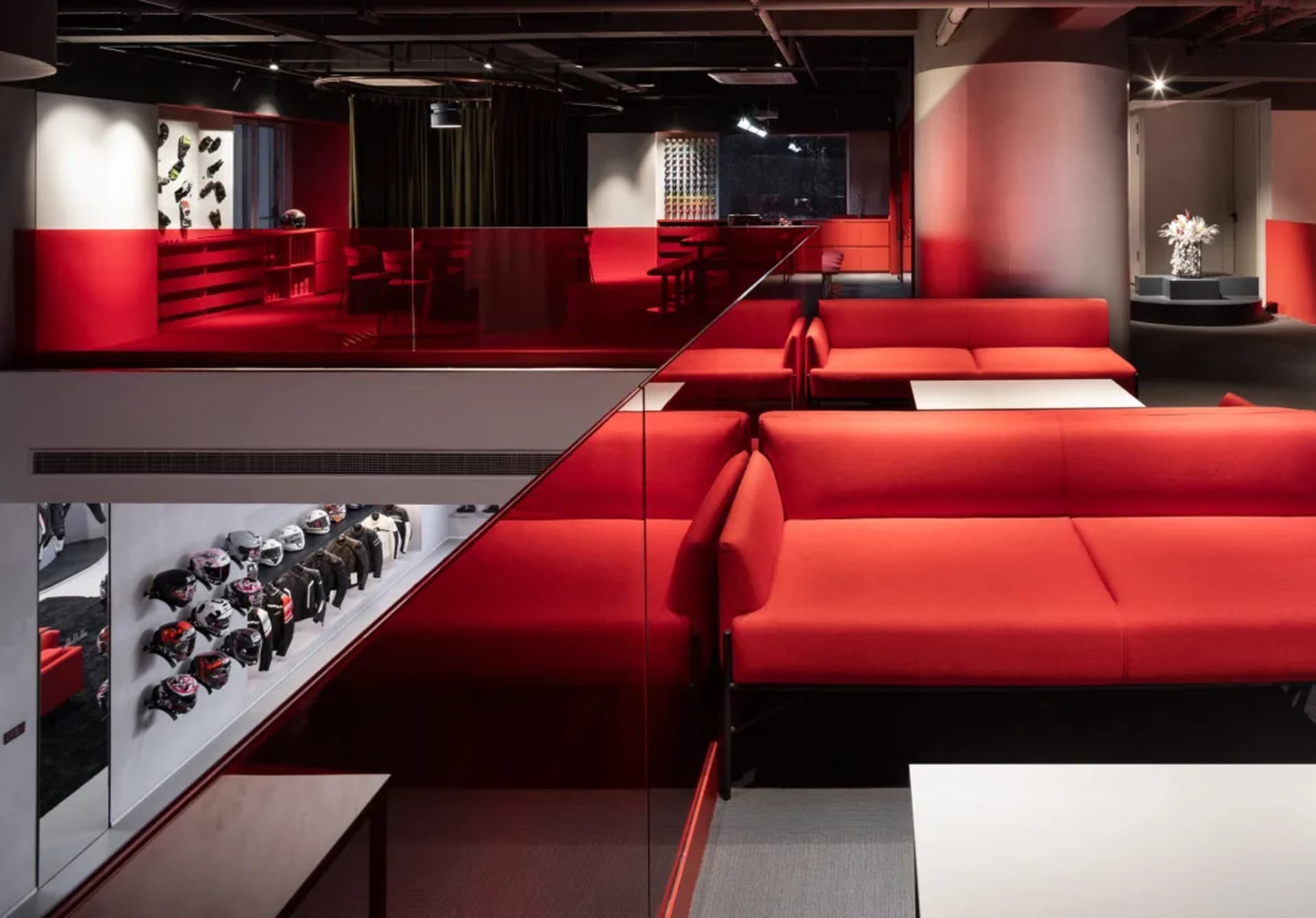 A modern living room with a red floor, glass walls, and a variety of furniture and decorative items