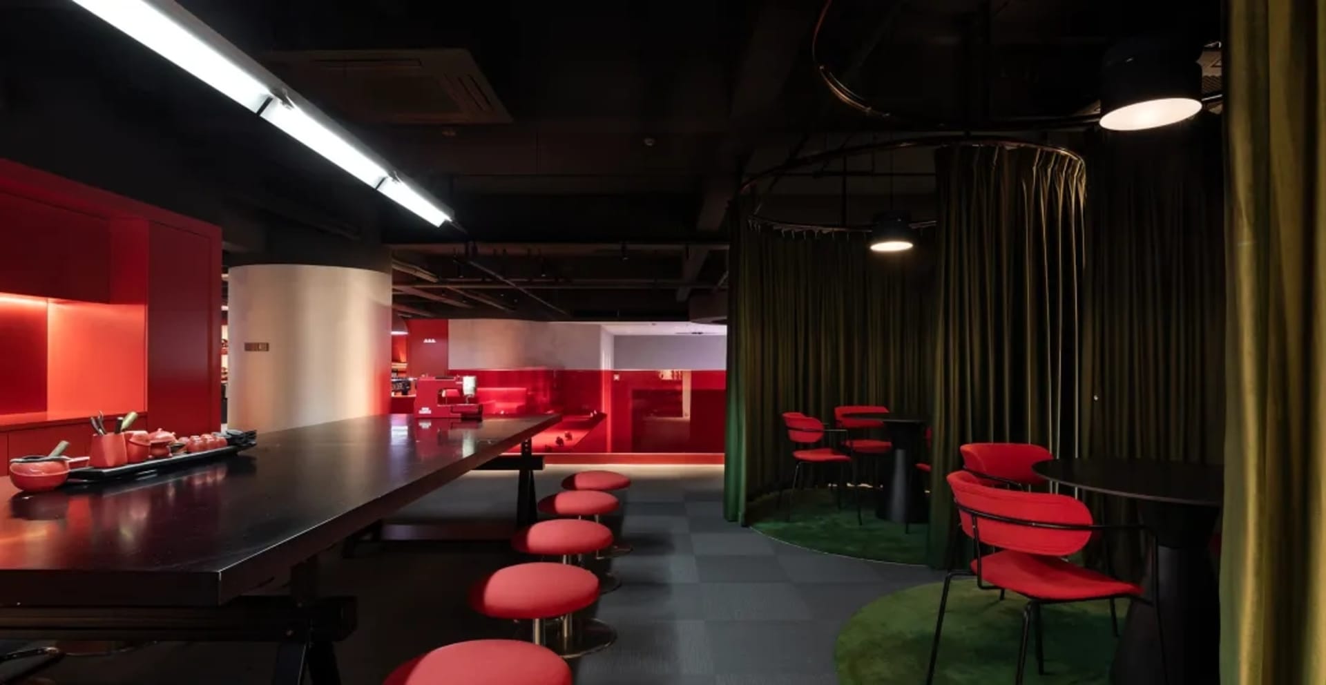 Cozy modern restaurant with a long bar, red accents, and dim lighting, encouraging social interaction