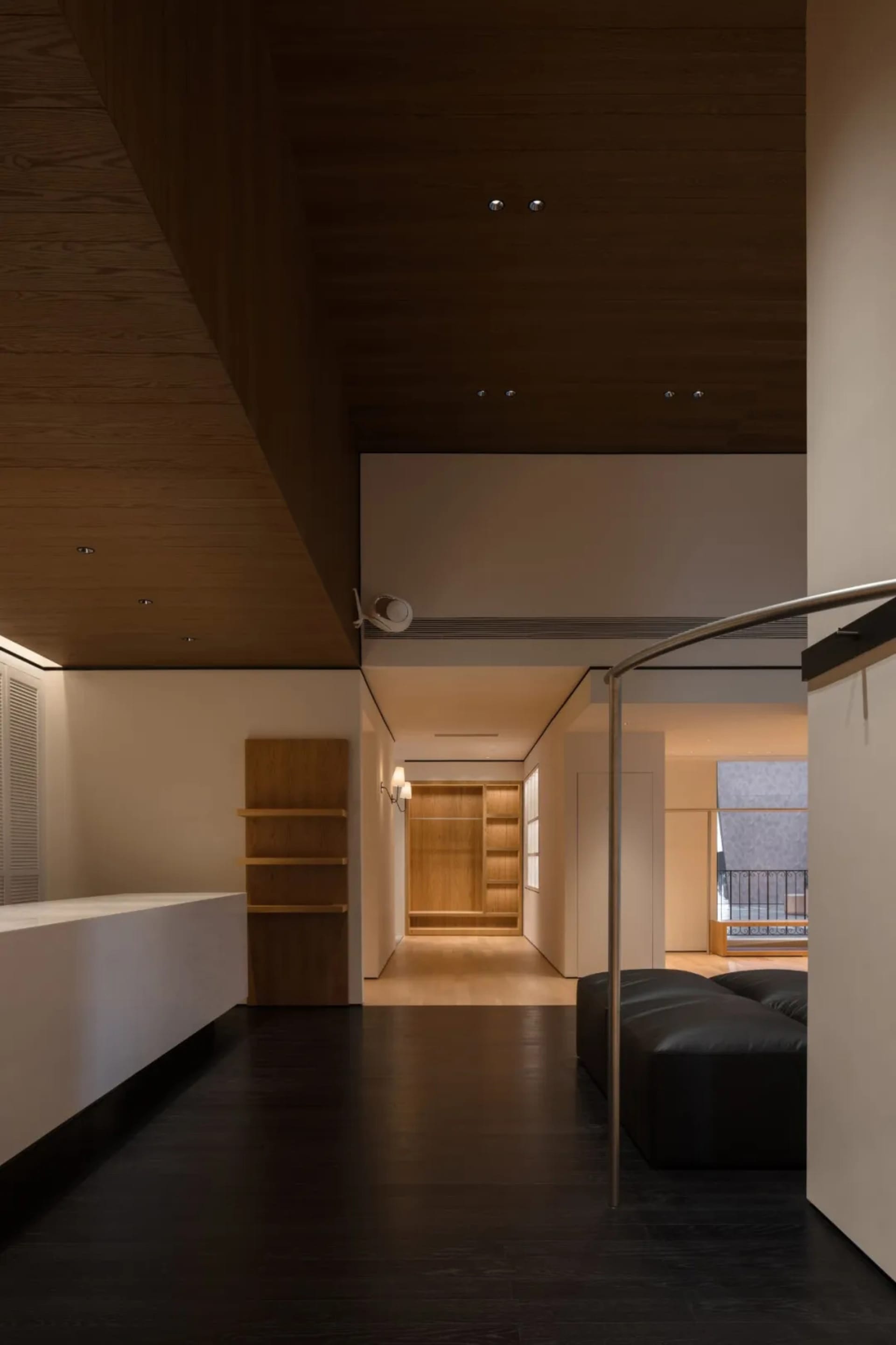 Open living space with a black couch, wooden elements, and a kitchen counter, featuring a warm and cozy atmosphere with dim lighting