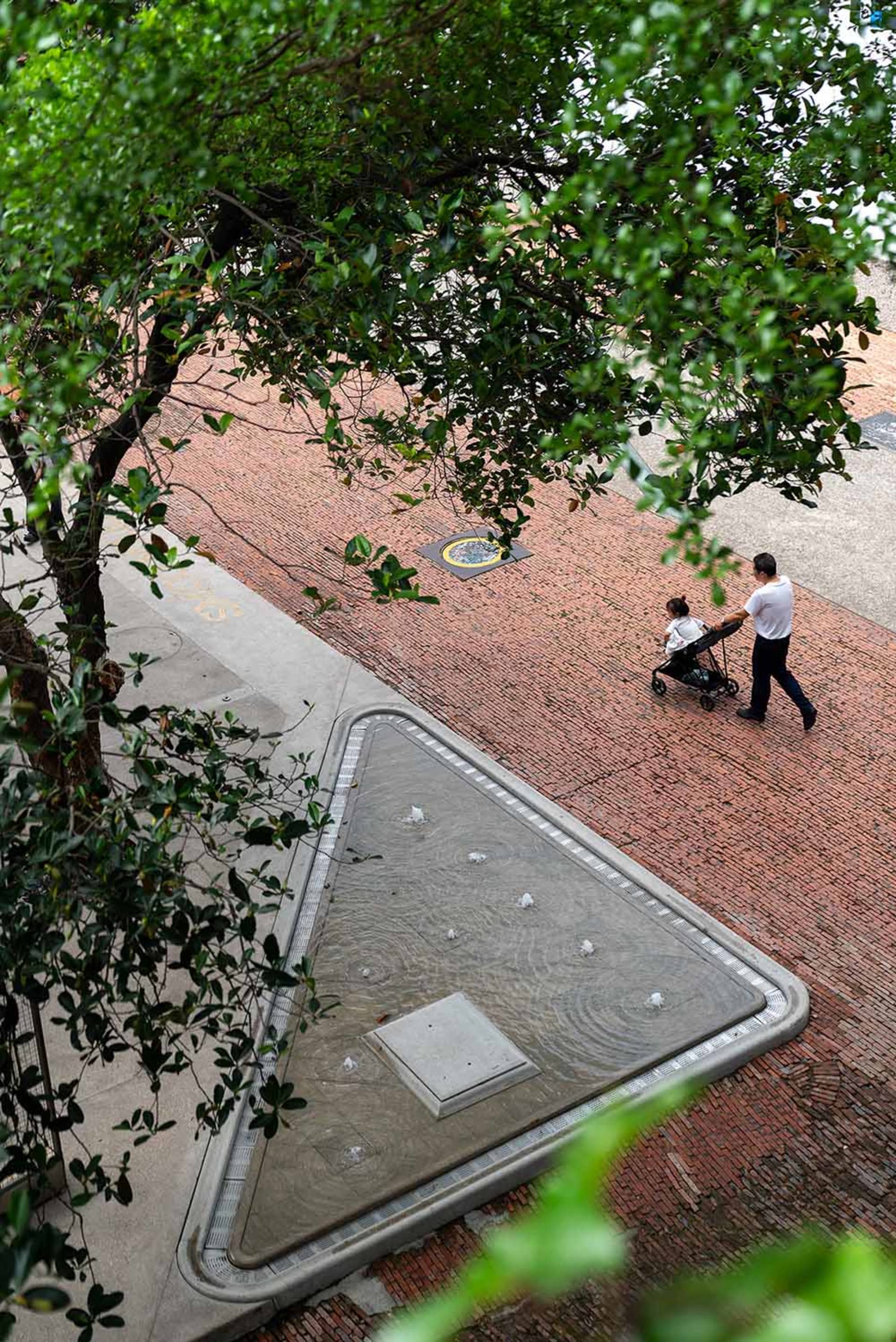 A man pushing a stroller on a brick sidewalk in an urban environment