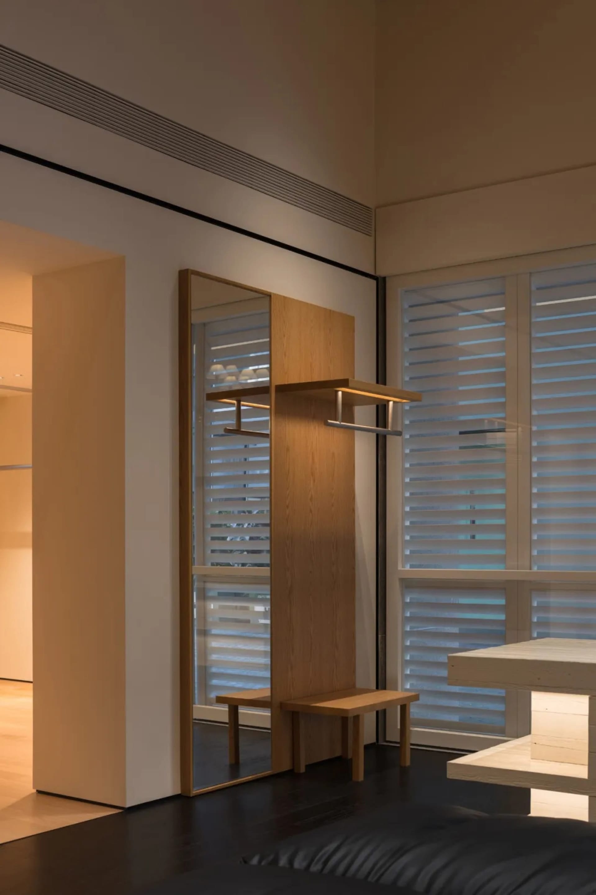Dining area with a wooden cabinet, table, chairs, and cups, set against a wooden floor and well-lit space