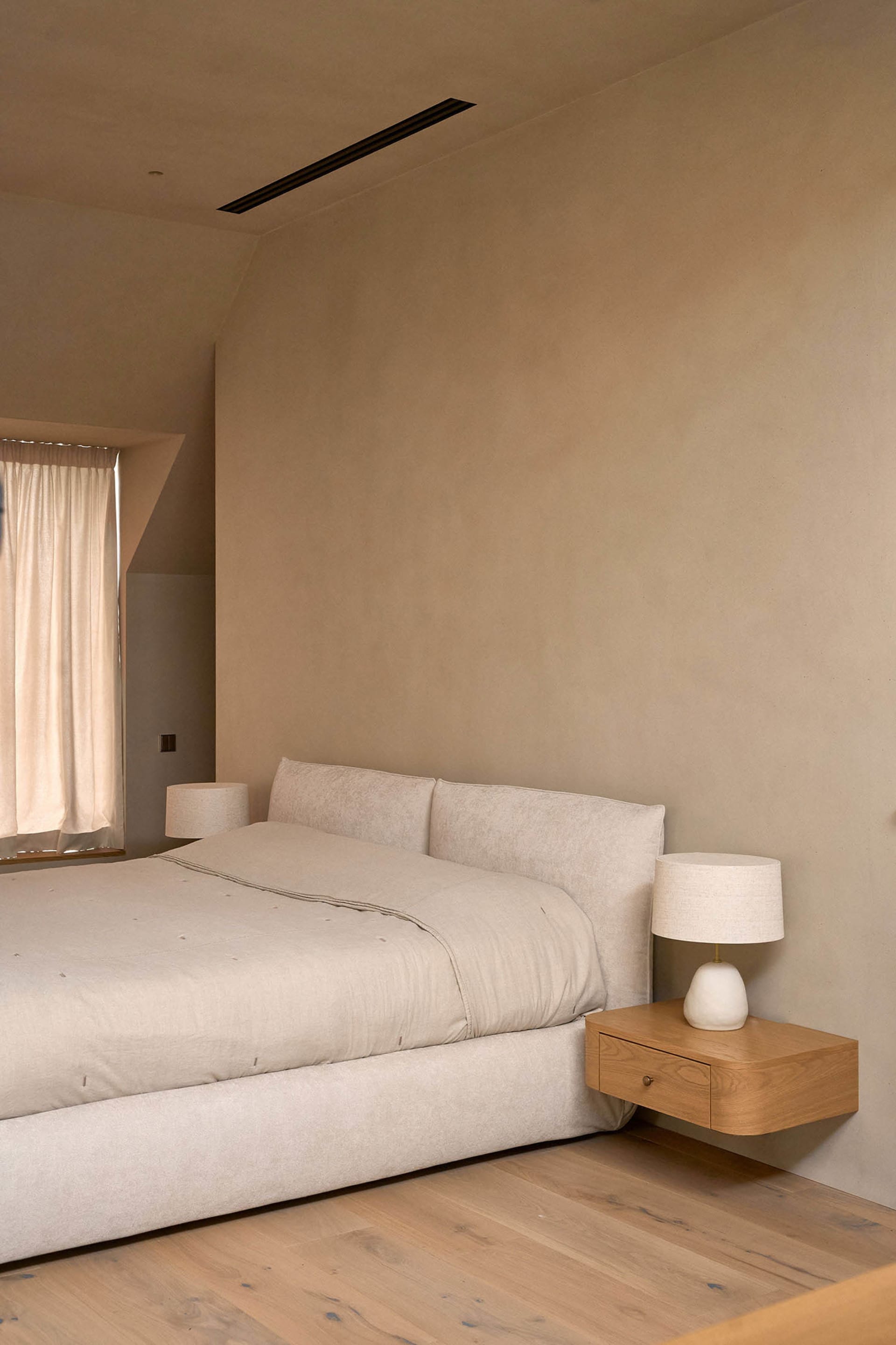溫馨臥室，配有白色床鋪、米色棉被、木質床頭櫃，以及從開啟窗戶灑入的自然光線