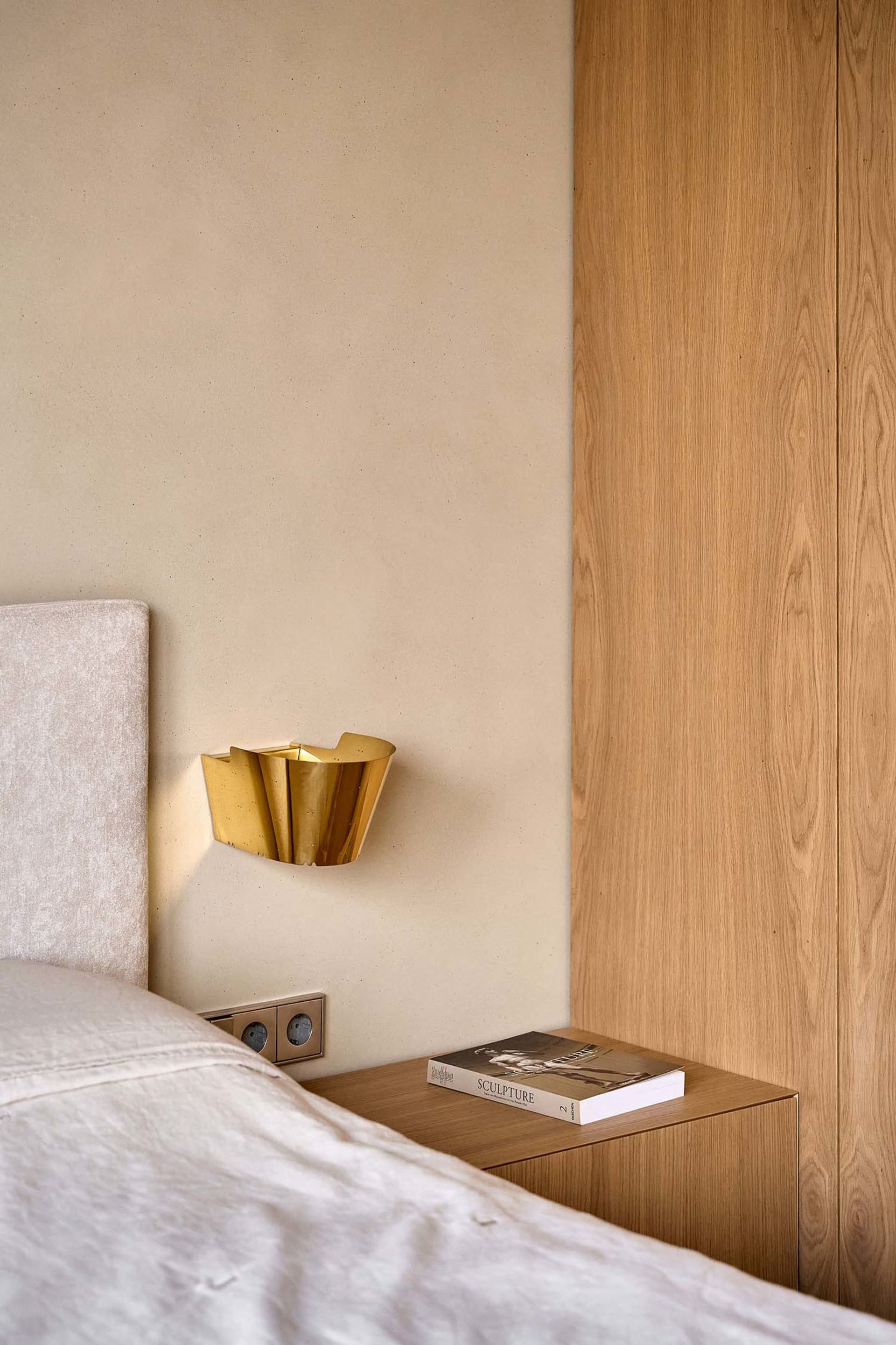 A cozy bedroom with a bed, bookshelf, and wooden wall, creating a warm and inviting atmosphere