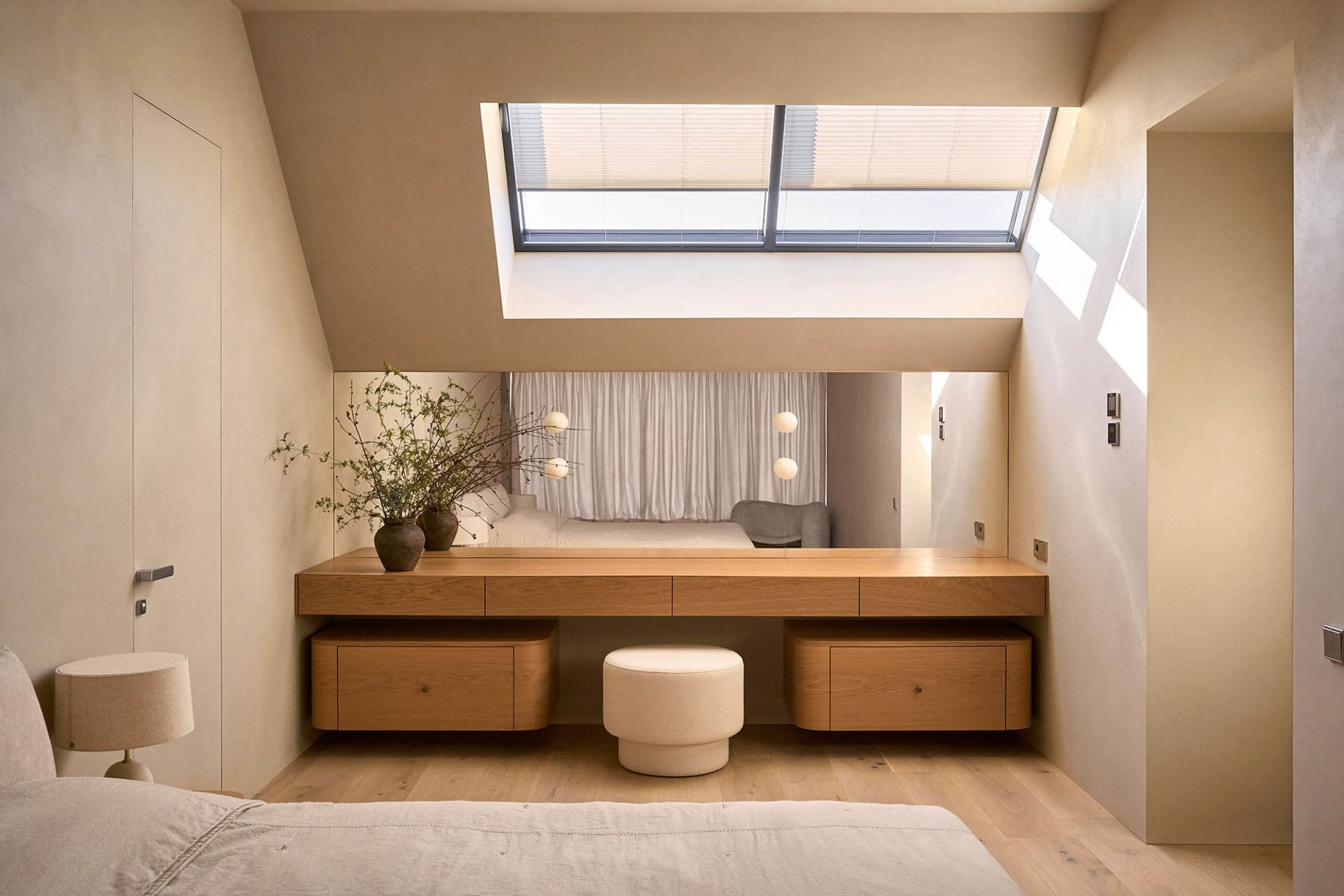 Cozy bedroom with a bed, chair, and dining table, featuring wood and glass materials, with natural light streaming in through the large window