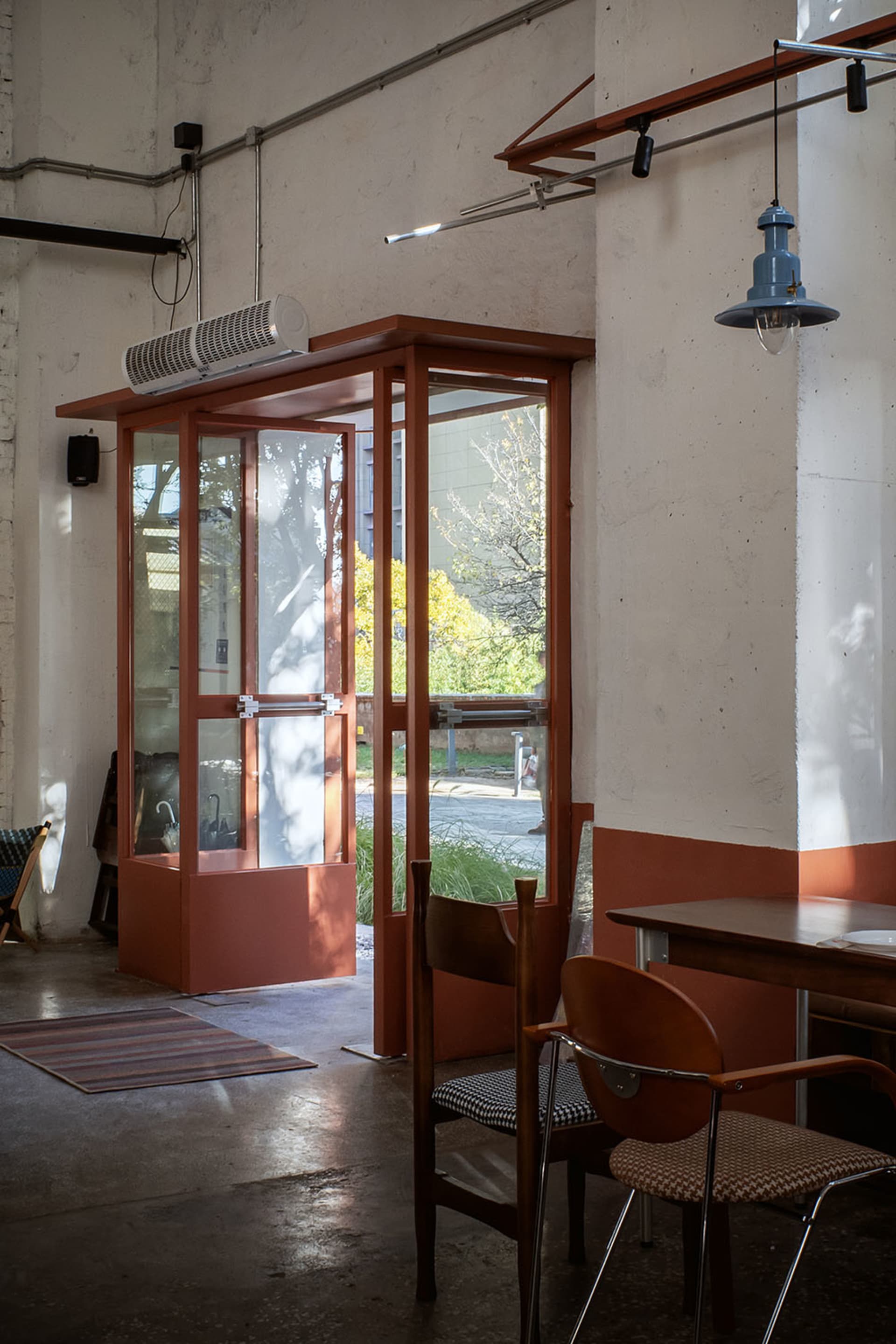 Dining room with a wooden table and chairs, natural light entering through an open door, and a modern style