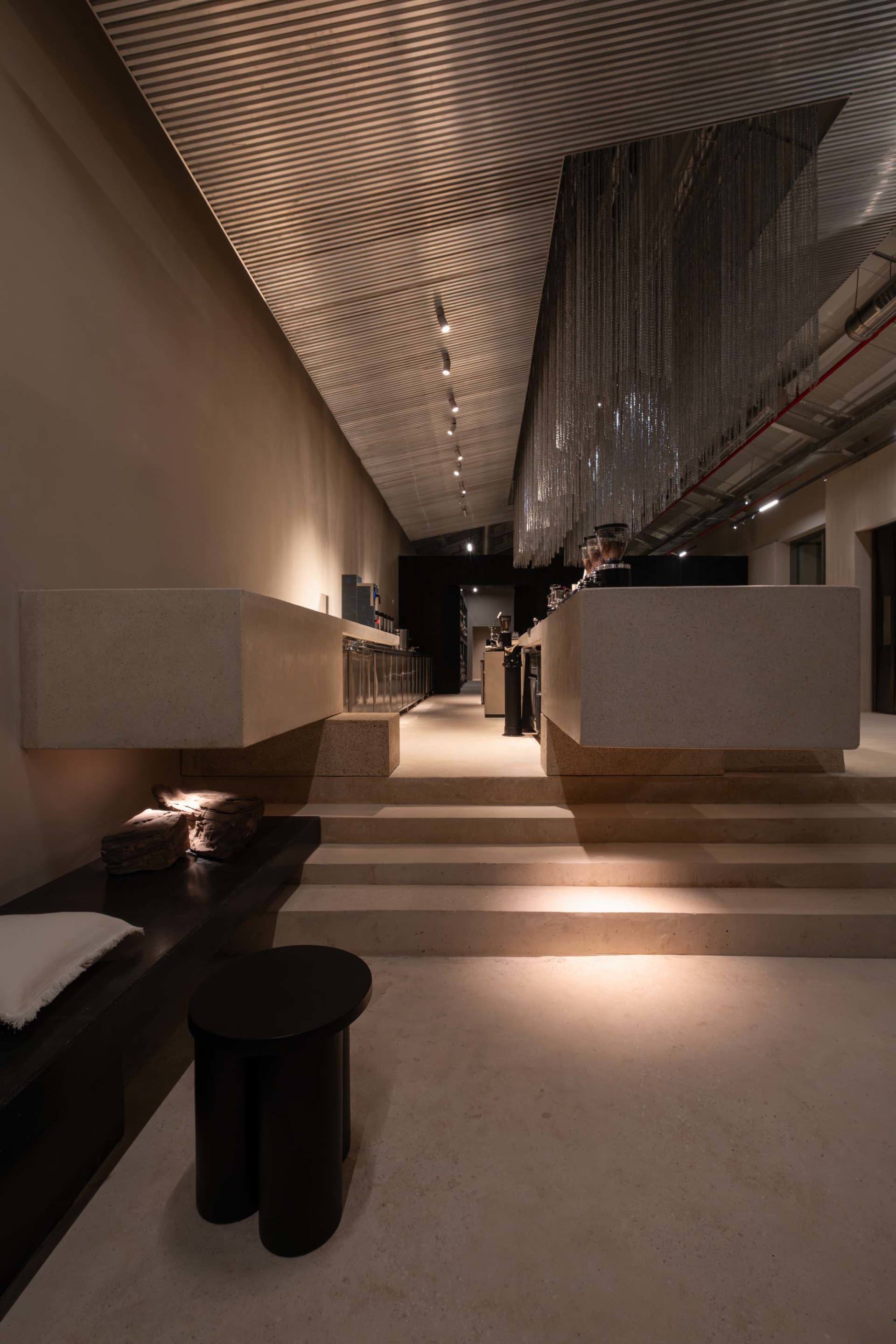 A dimly lit lobby with a staircase made of concrete and a counter made of marble, creating a sophisticated atmosphere