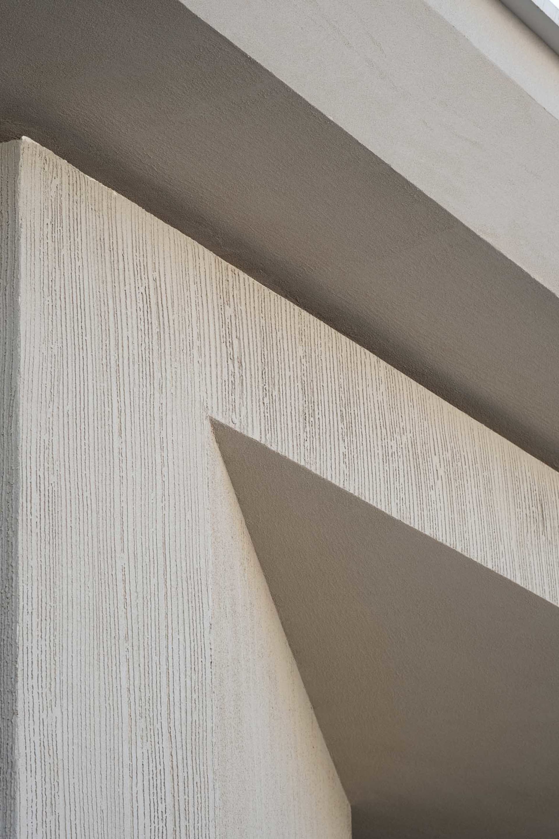 A modern building with a white wall and grey floor, featuring a white and grey color scheme and natural lighting