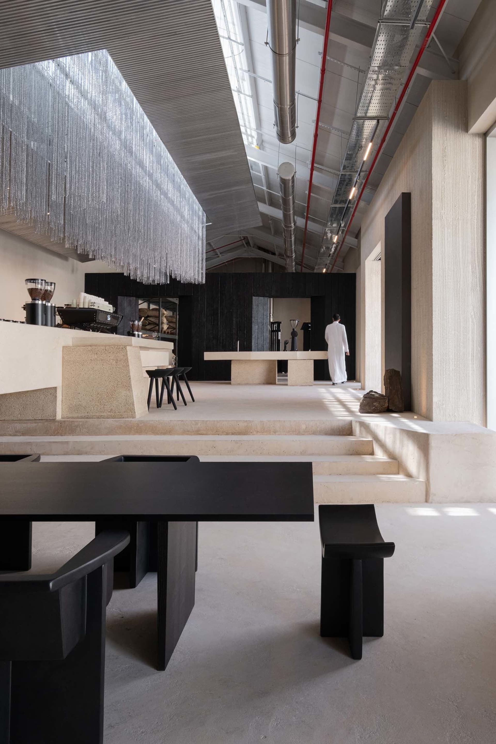 Modern open-plan room with a concrete floor, dining area, kitchen, and metal accents