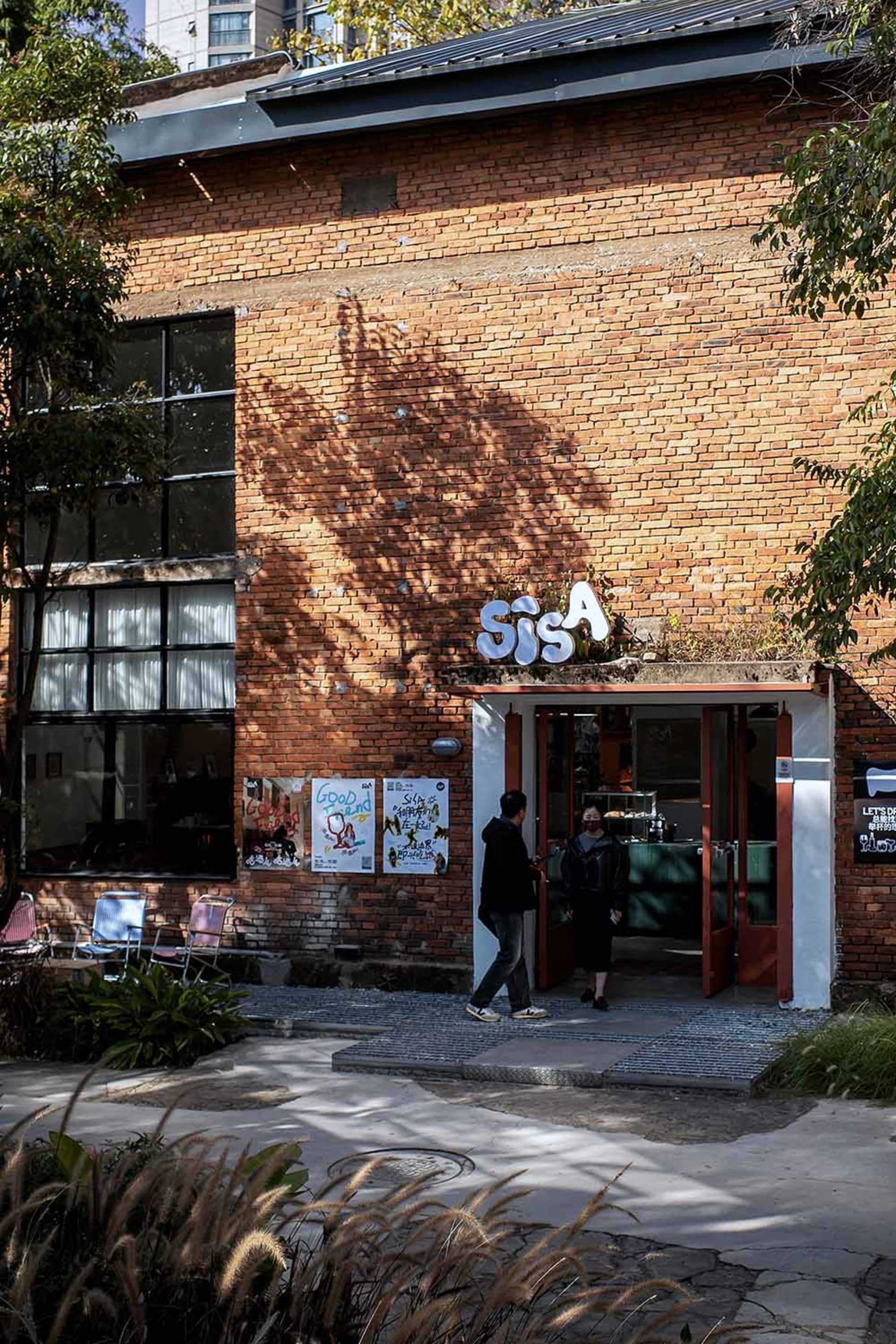 一間休閒餐廳磚牆立面，人們進進出出，前景有一張椅子