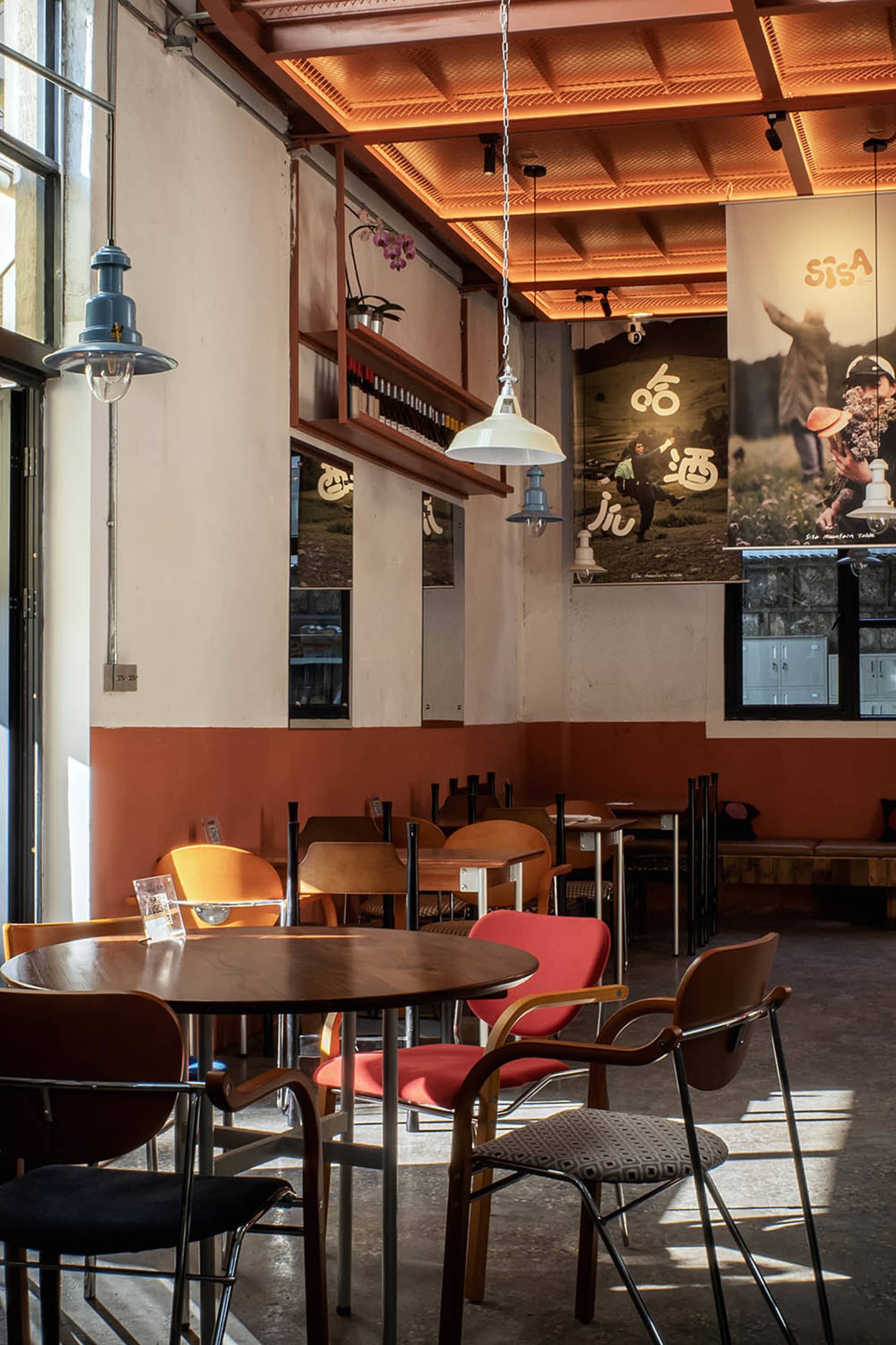 A dimly lit restaurant interior with a table and chairs, surrounded by wood and metal furniture, decorative plants, and vases, creating a warm and inviting atmosphere