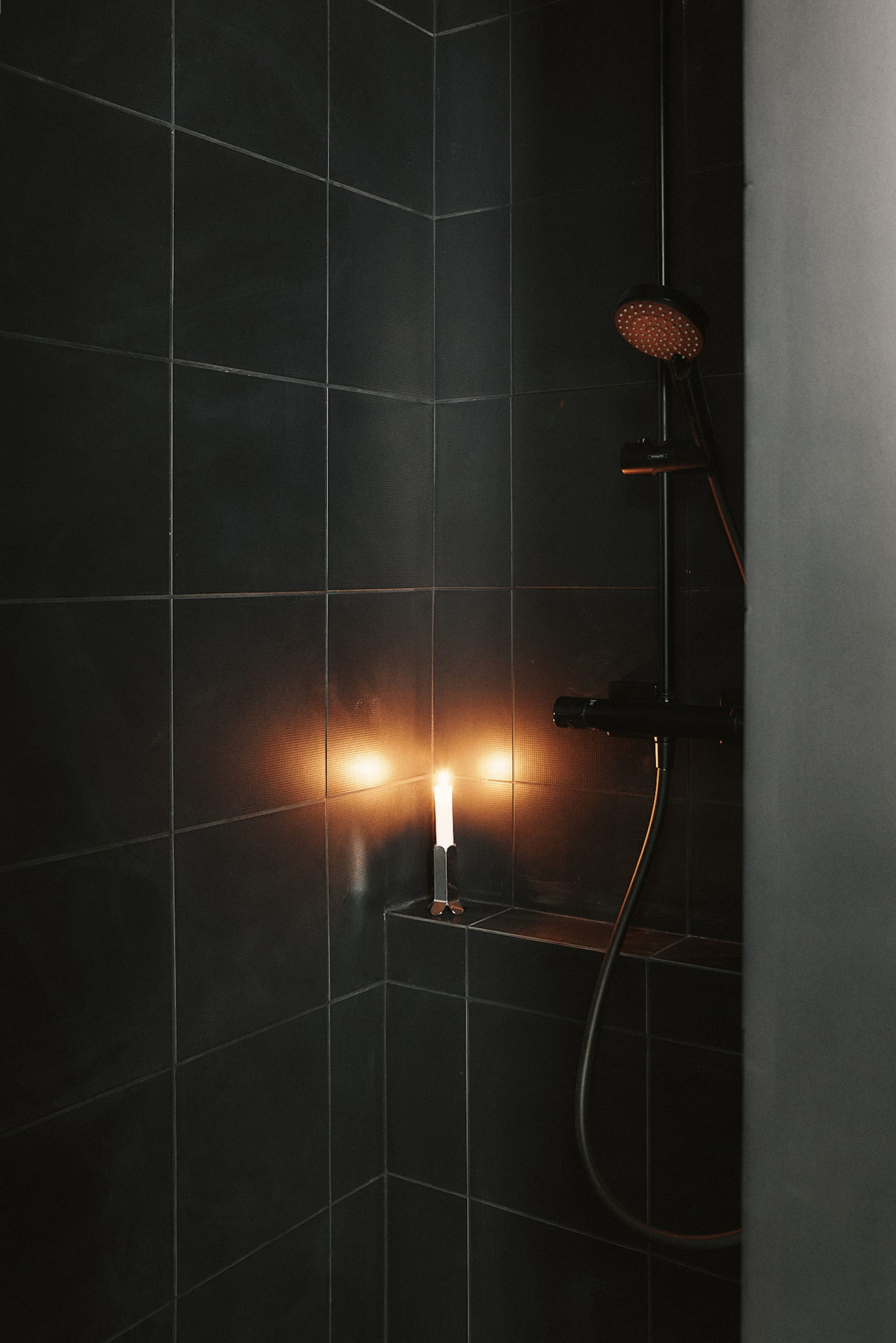 A modern bathroom with a glass shower, toilet, and sink, featuring tiled walls and dim lighting