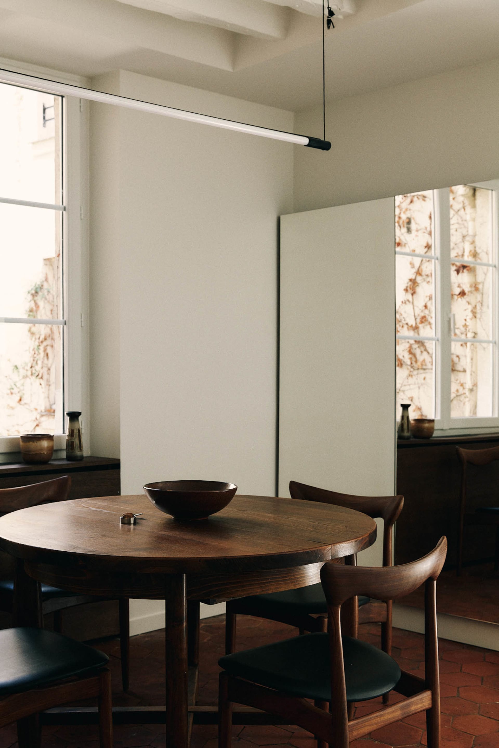 Dining room with a wooden table and chairs, surrounded by a wooden floor and a window with natural light