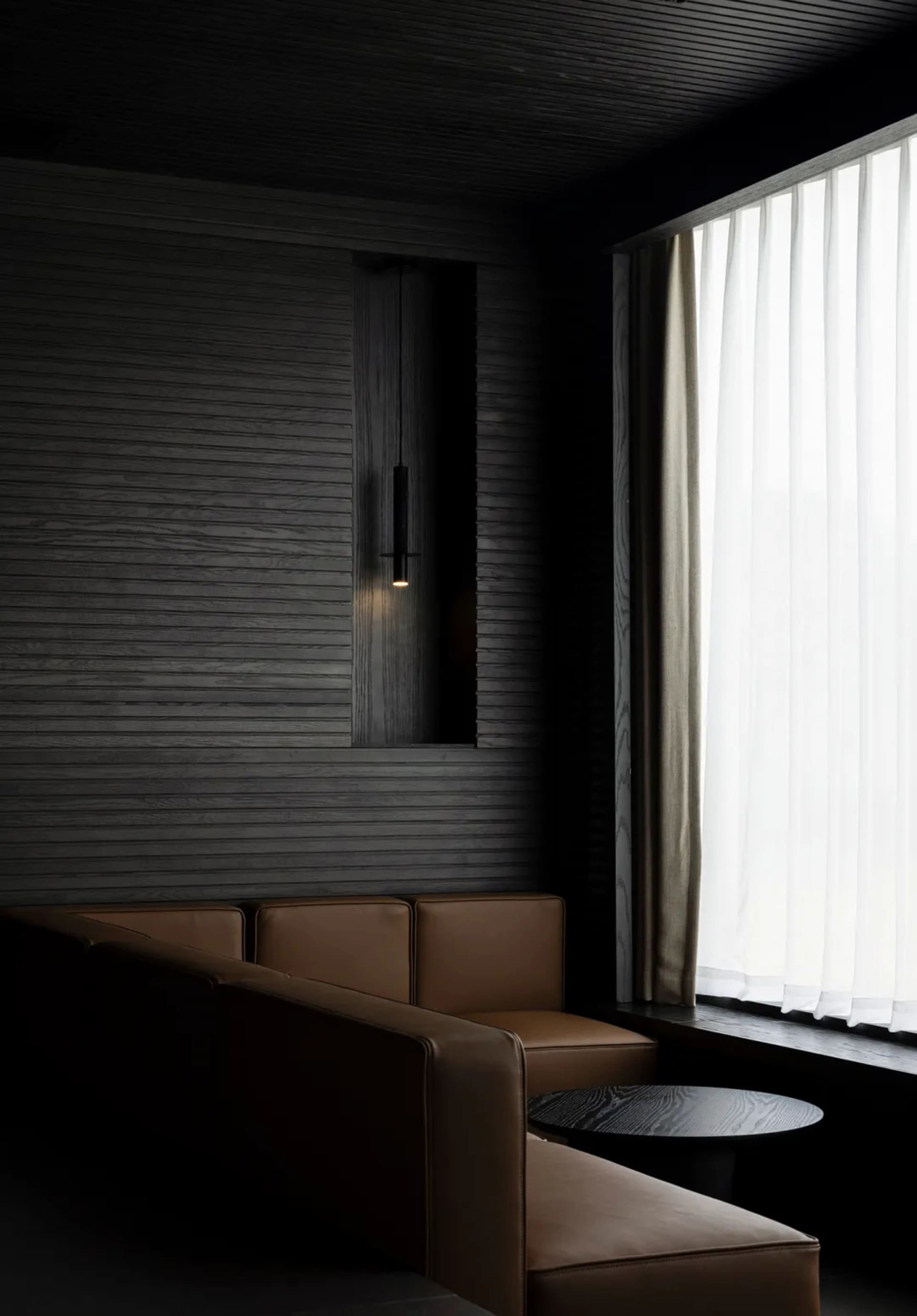 Cozy living room with a black and white color scheme, leather furniture, and a lamp near a window