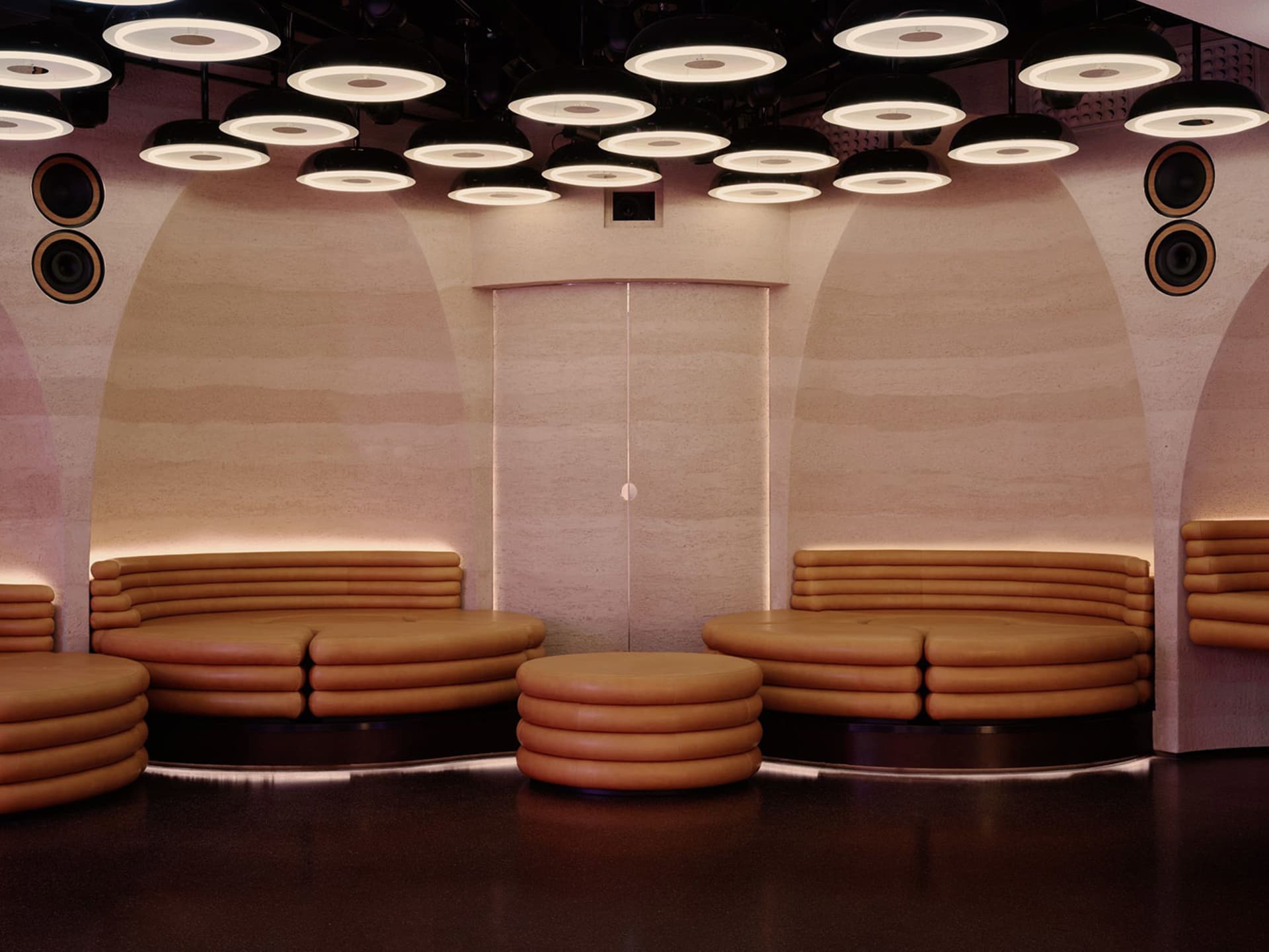 A modern living space with a semi-circular seating arrangement, featuring couches and chairs, in a room with a mix of natural and artificial light sources