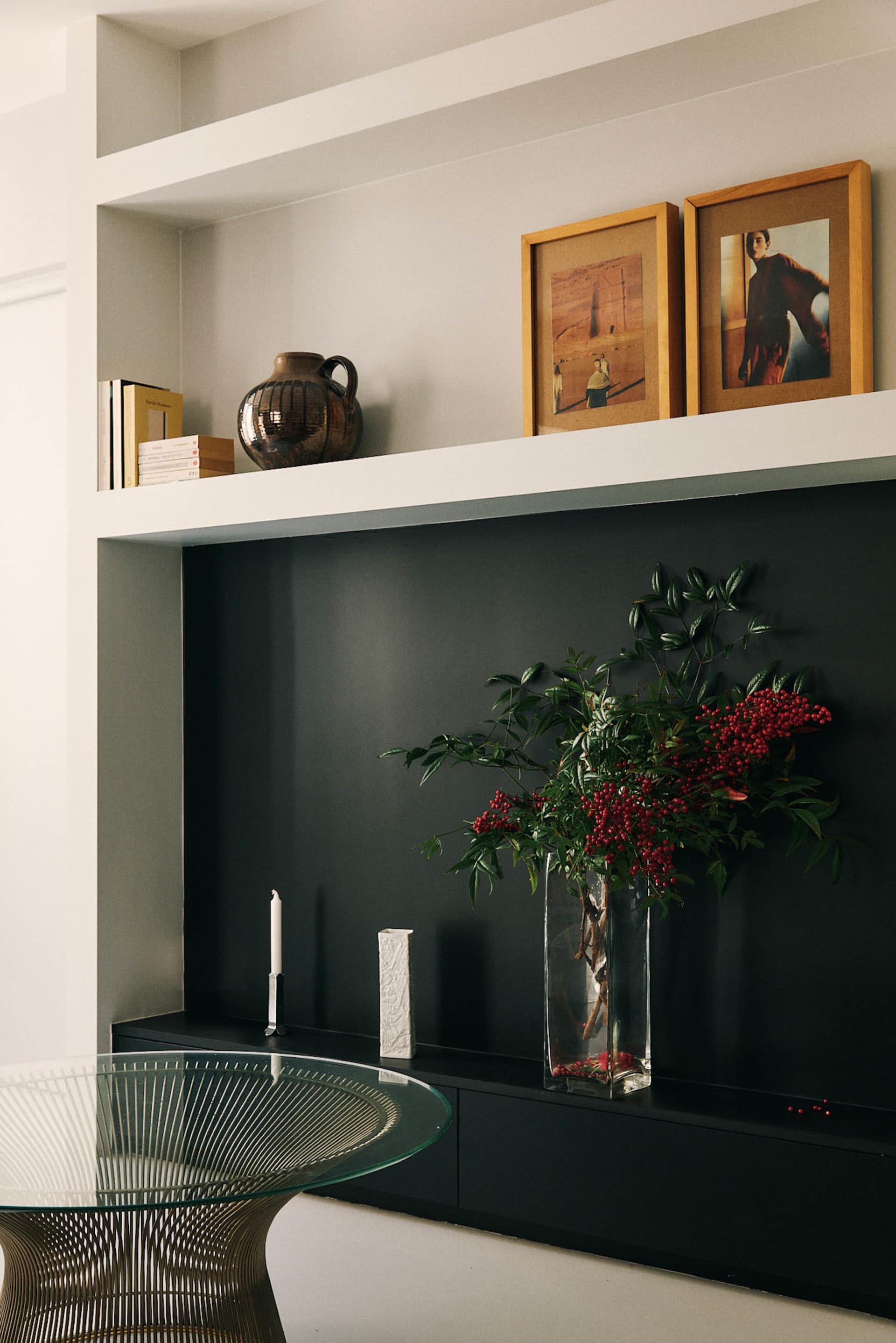 Cozy modern living space with a black shelf, a couch, and a dining table, featuring a dimly lit atmosphere and a black and white color scheme