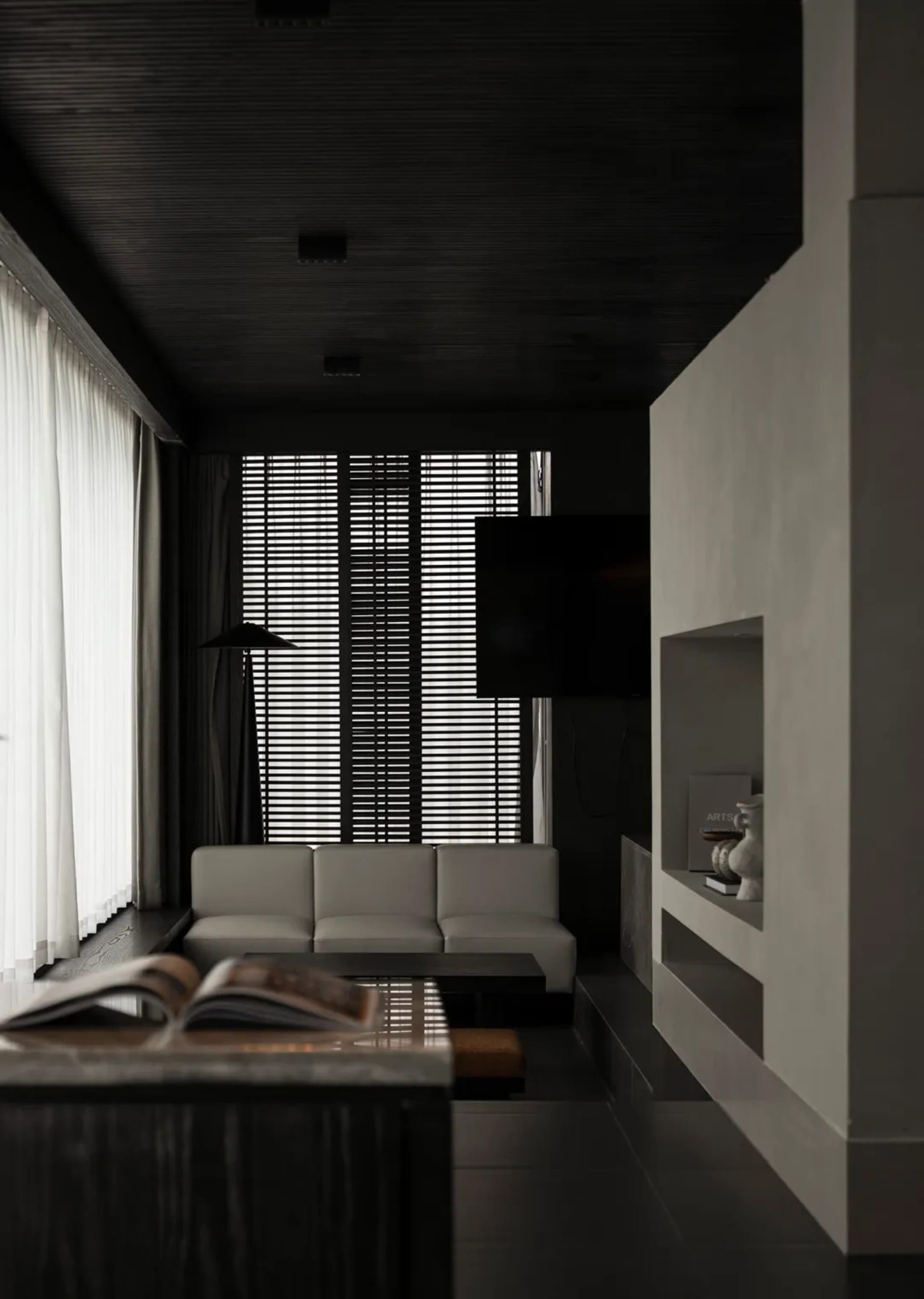 A well-lit living room with a white couch, a black chair, and a television on a stand, set against a black and white color scheme