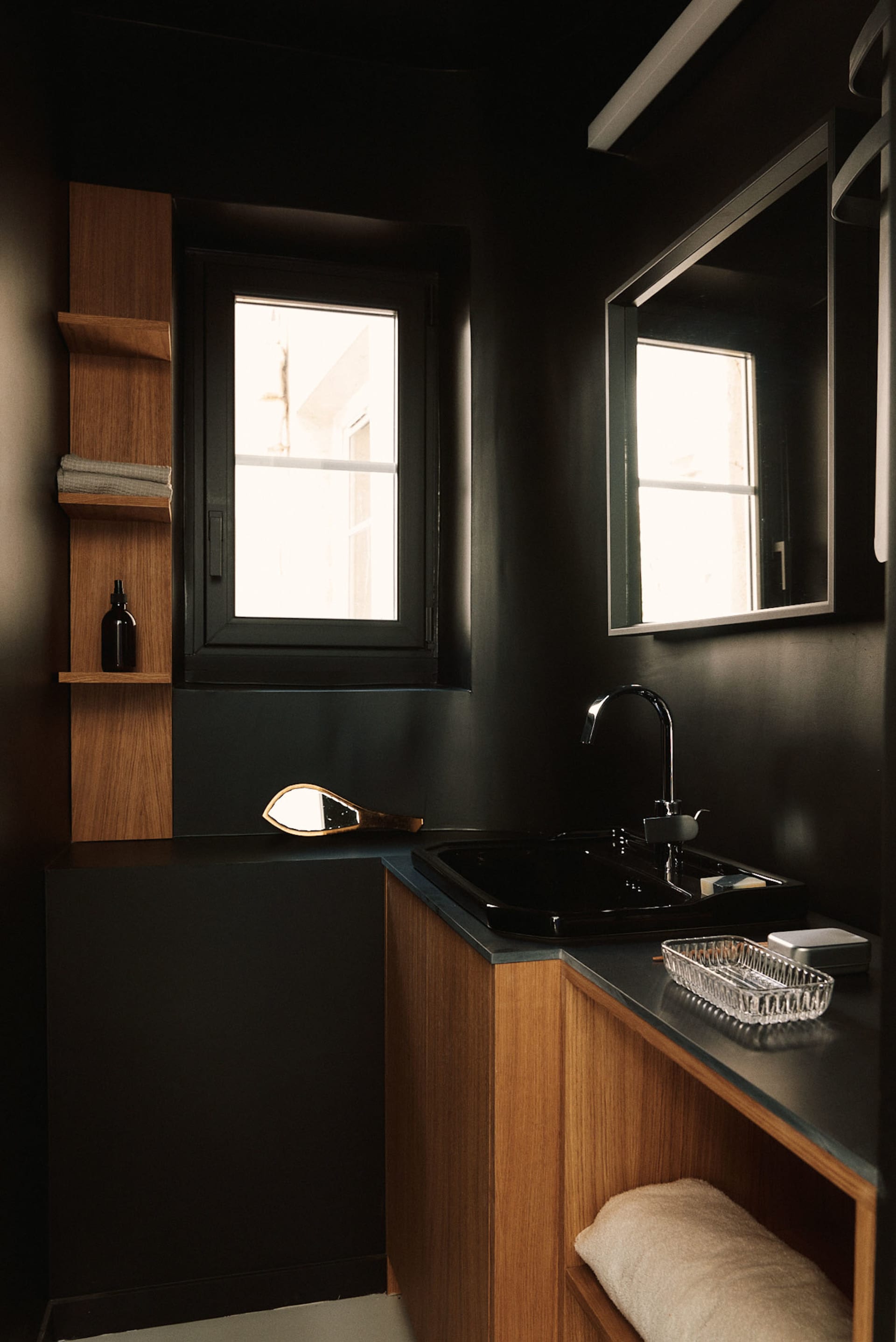 Black and white photograph of a minimalist bathroom with a sink, mirror, and window, featuring a sleek and modern aesthetic