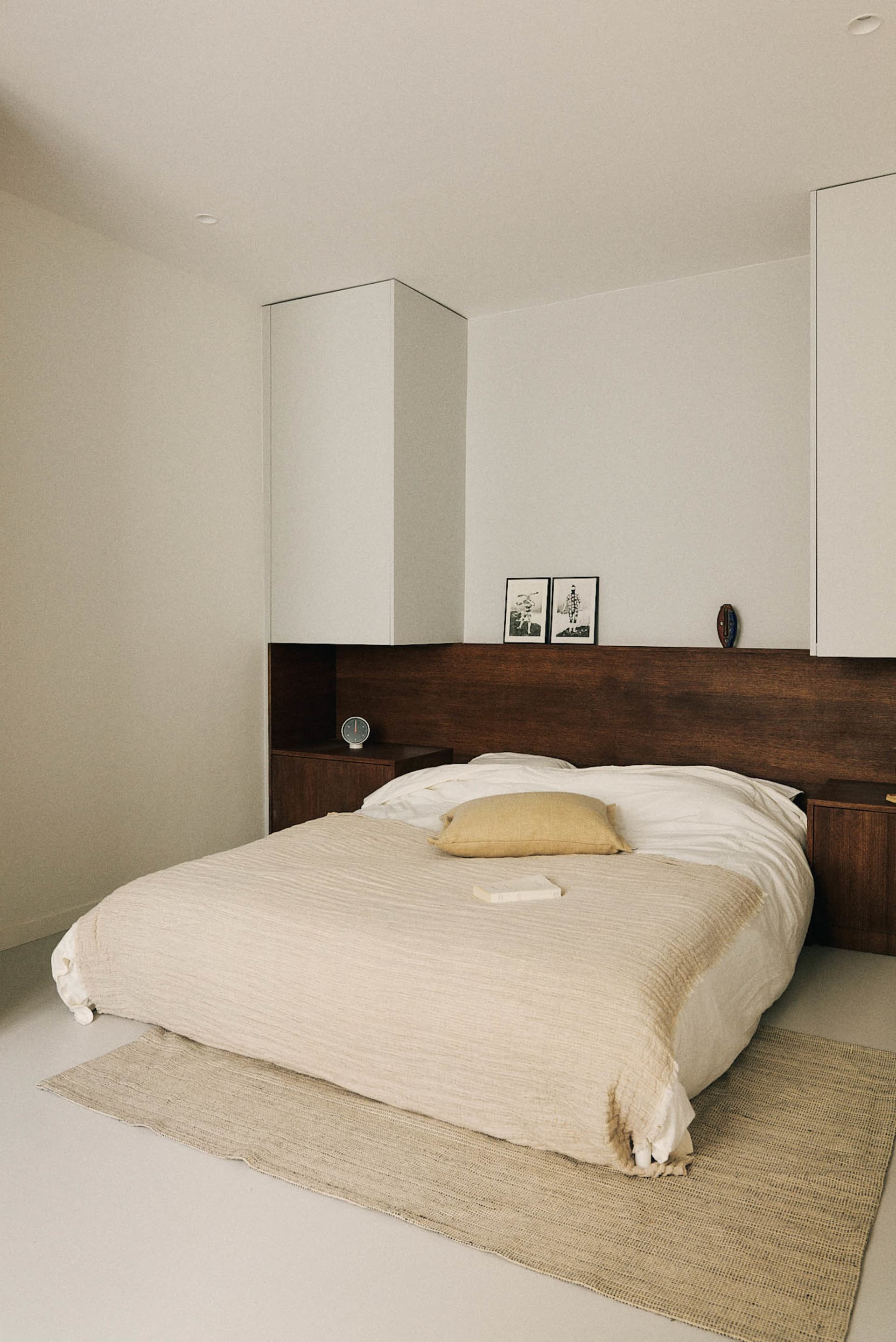 Cozy modern bedroom with a bed, nightstand, and dresser, featuring wood furniture and a warm atmosphere