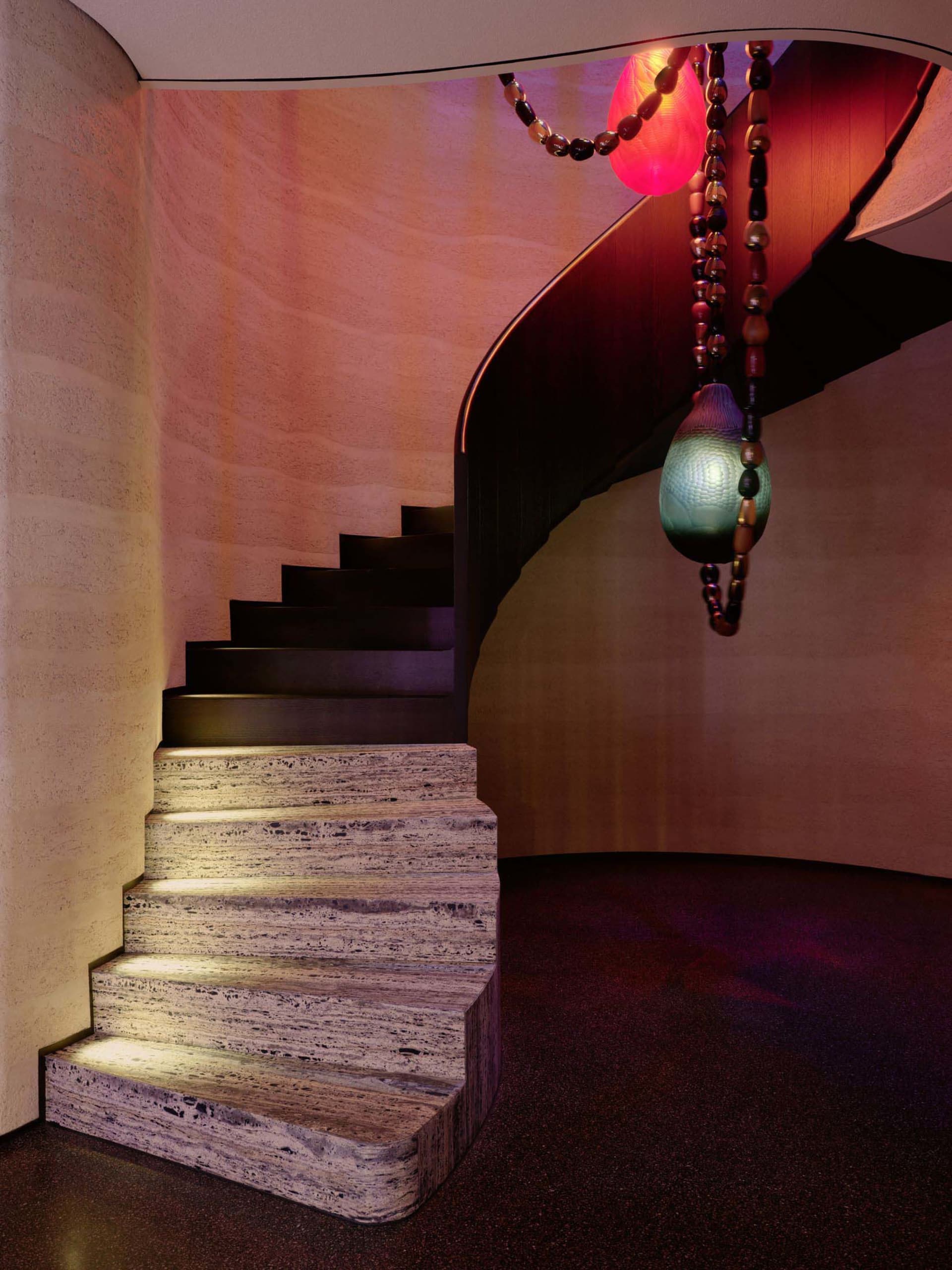 A stone staircase with a metal railing in a well-lit hallway, creating a warm and inviting atmosphere