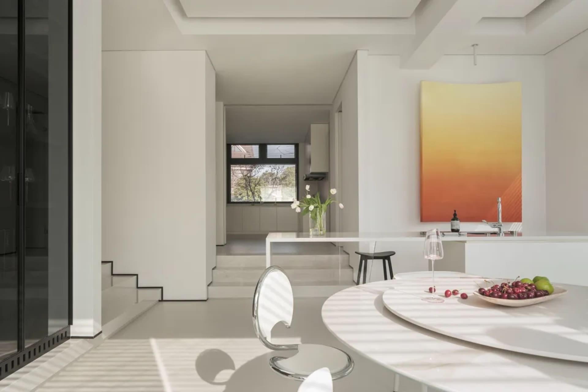 A modern kitchen and dining space with white countertops, a dining table, chairs, potted plants, and vases, in a minimalist and contemporary style