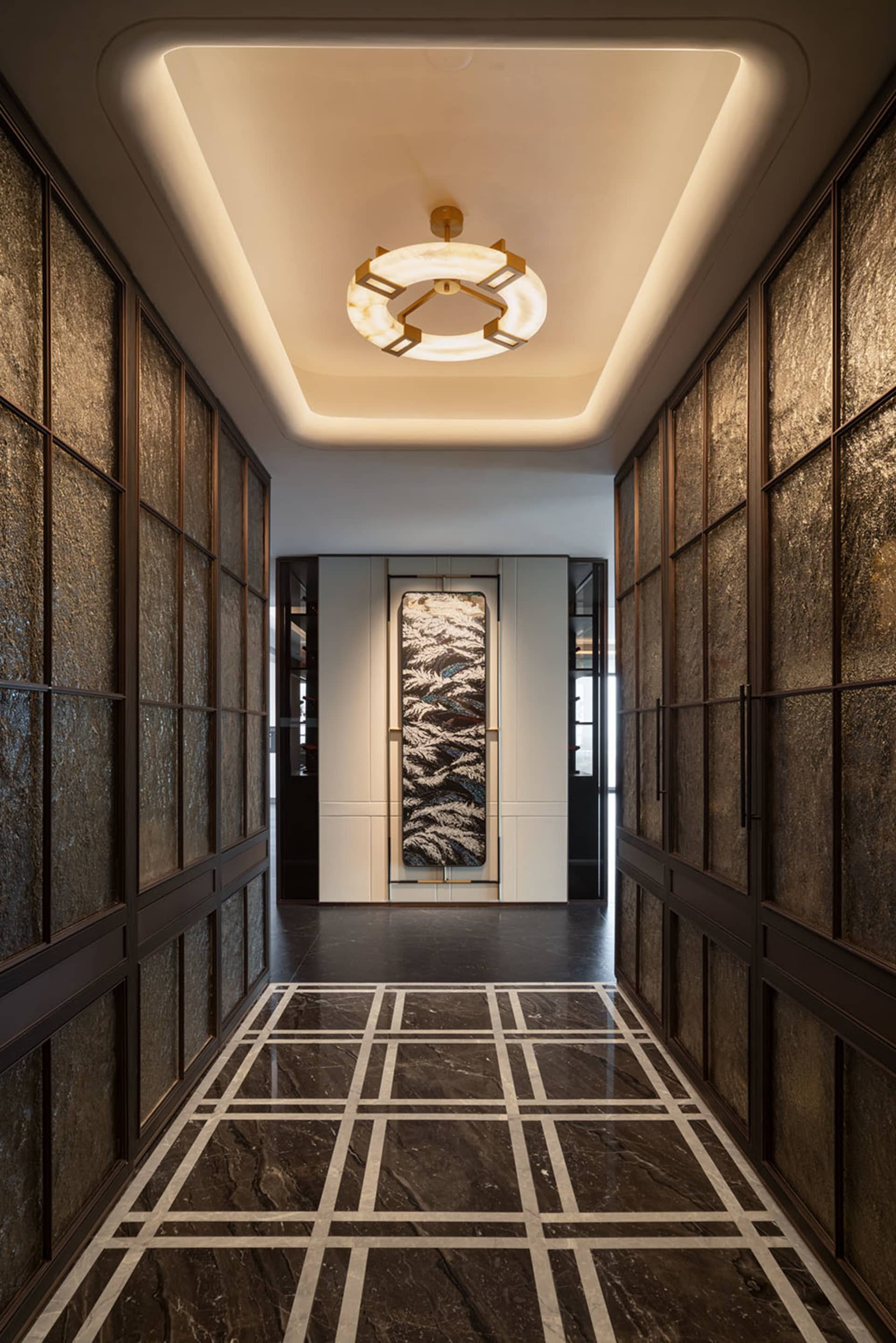 A modern hallway with a black and white color scheme, a large painting on the wall, and a doorway leading to a living room area, with marble flooring and dim lighting