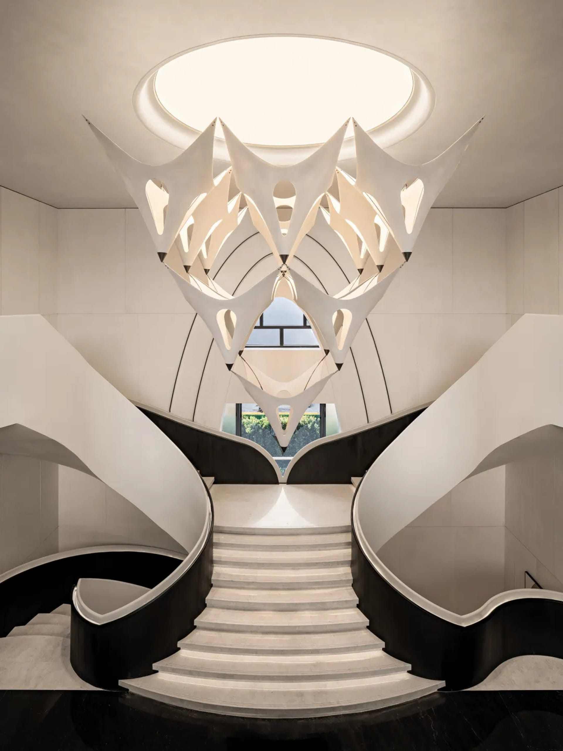 A modern staircase with a white railing and white stone wall, bathed in natural sunlight