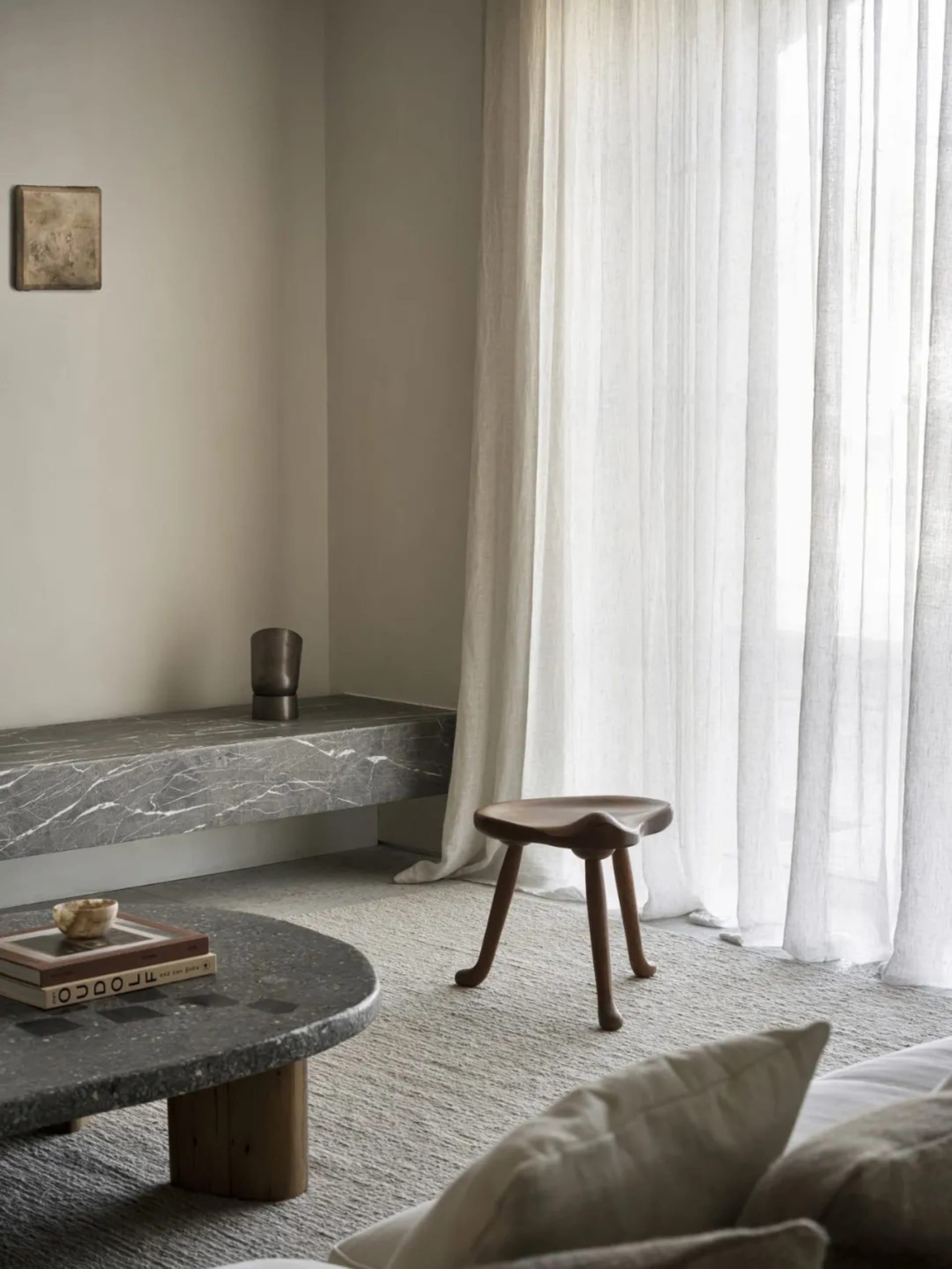 Cozy modern living space with a stone countertop, stone table, and natural light from windows, featuring a couch, chair, and coffee table