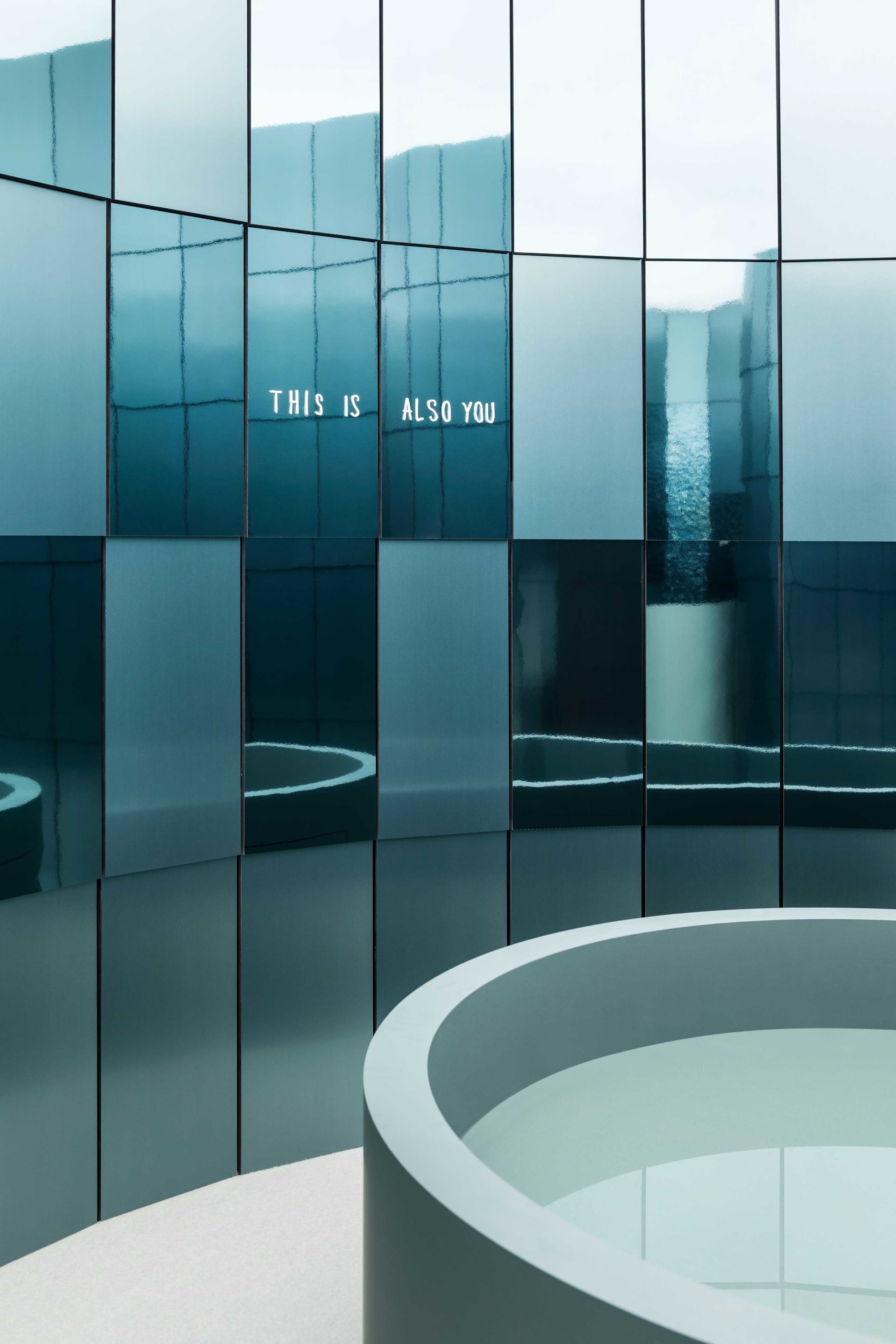 A modern room with a circular mirror on the wall, surrounded by a circular frame, in a blue color scheme, with a clean and minimalistic atmosphere