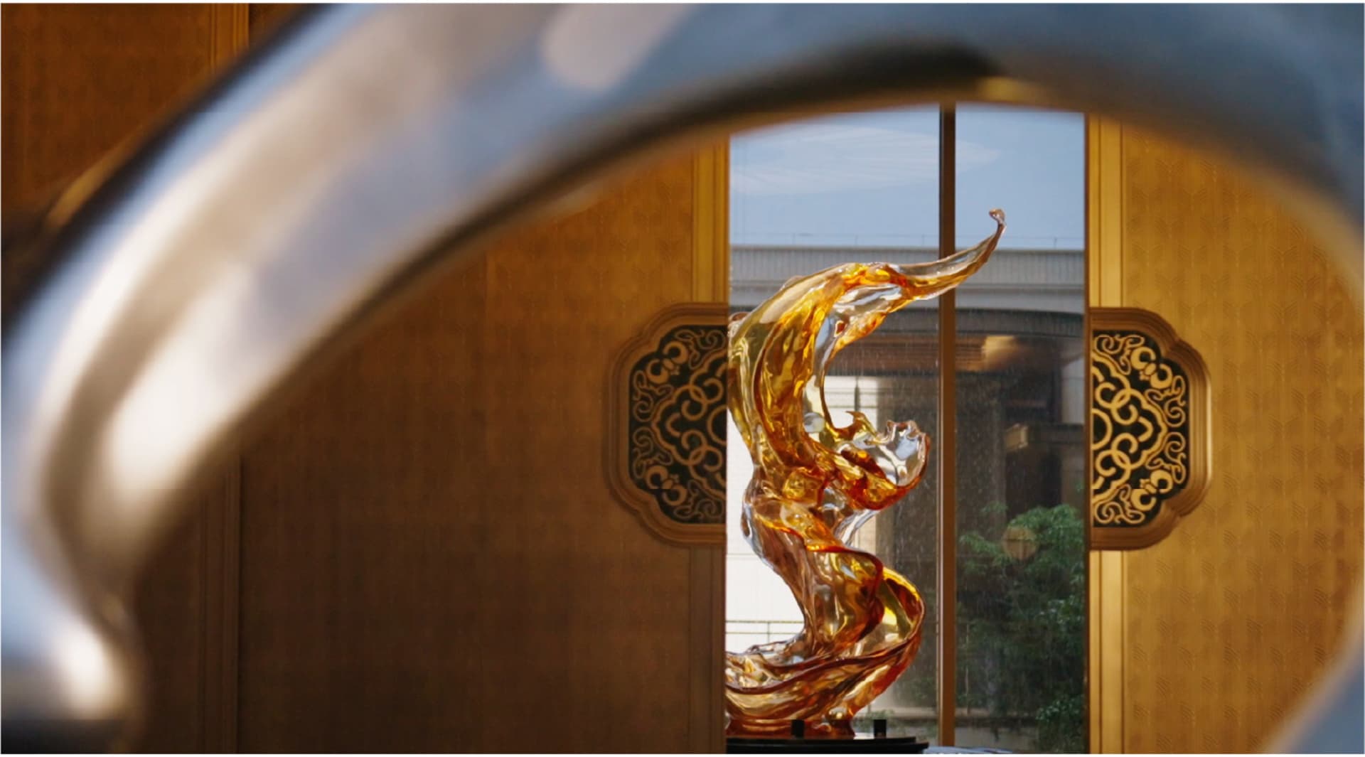 A modern room with a large glass metal and wood sculpture, elegant and sophisticated design, natural and artificial lighting