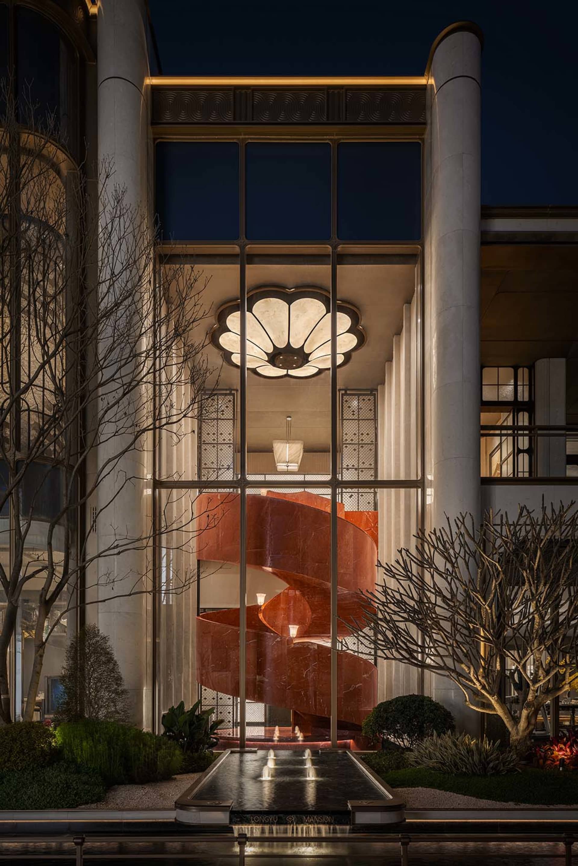 A modern building with a prominent red marble staircase, set against a dimly lit background