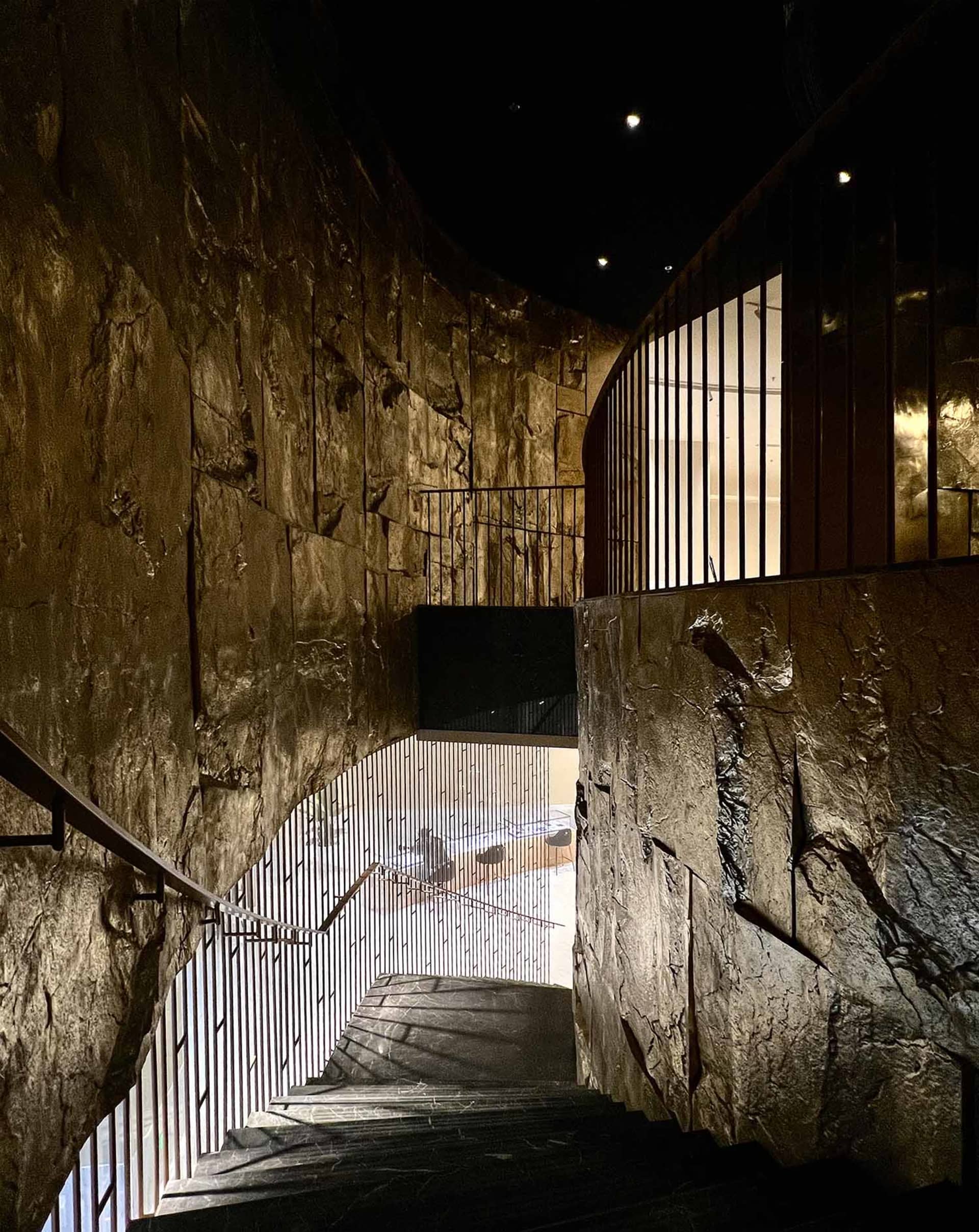 A dimly lit underground stairwell with stone stairs and walls