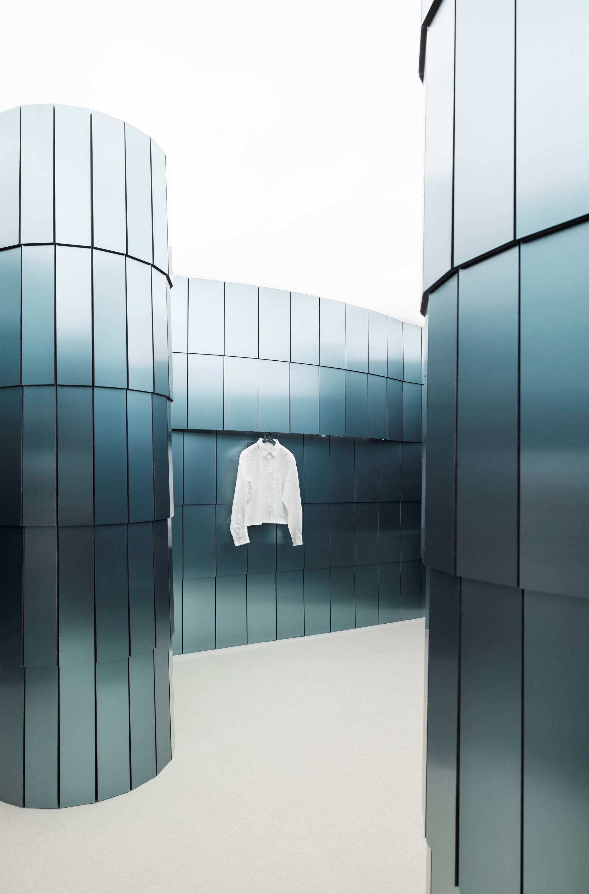A modern room with a blue color scheme, a white shirt hanging on a hook, and a clean and organized atmosphere