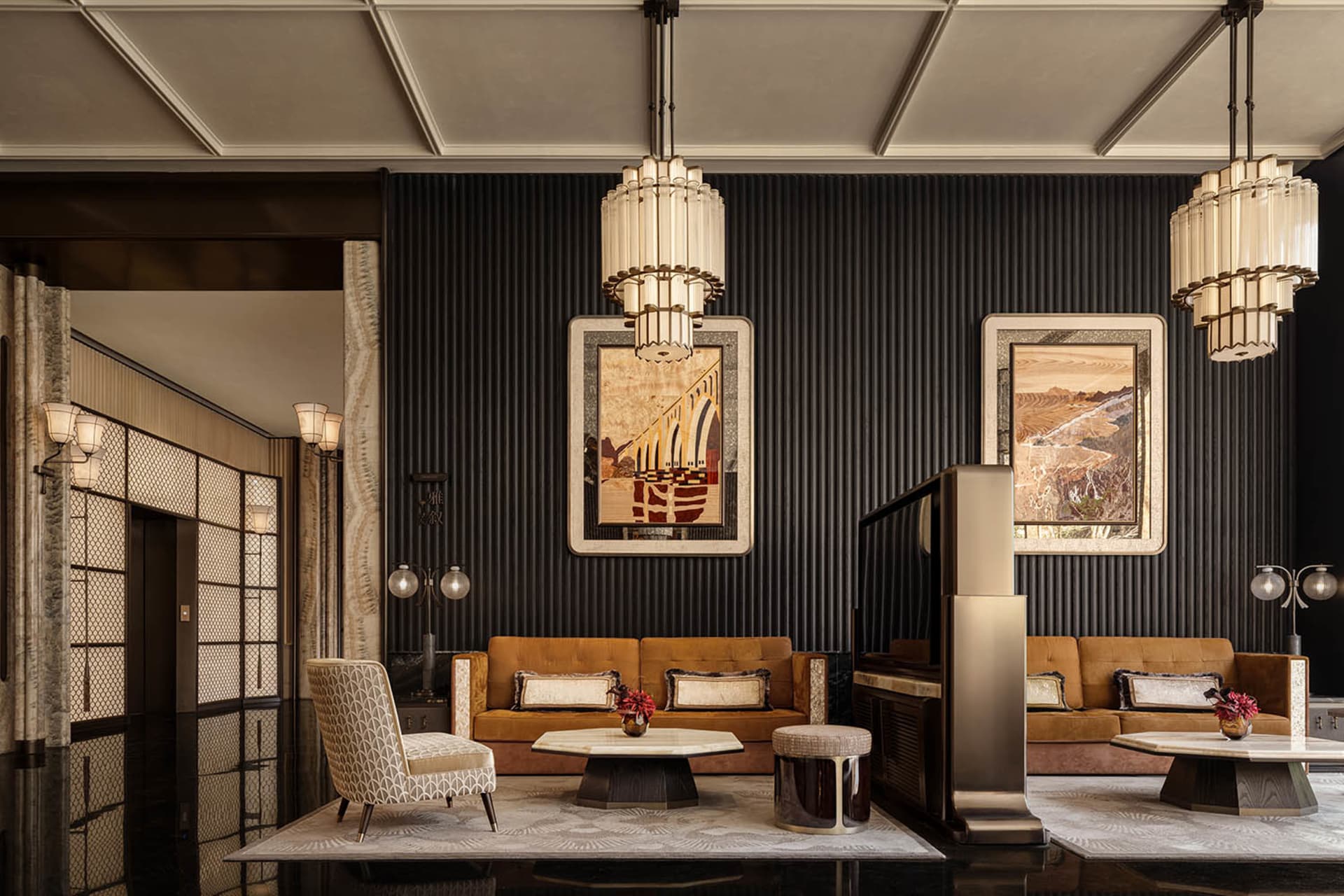 A dimly lit living room with a metal chandelier, a couch, a chair, and a dining table in a black and white color scheme