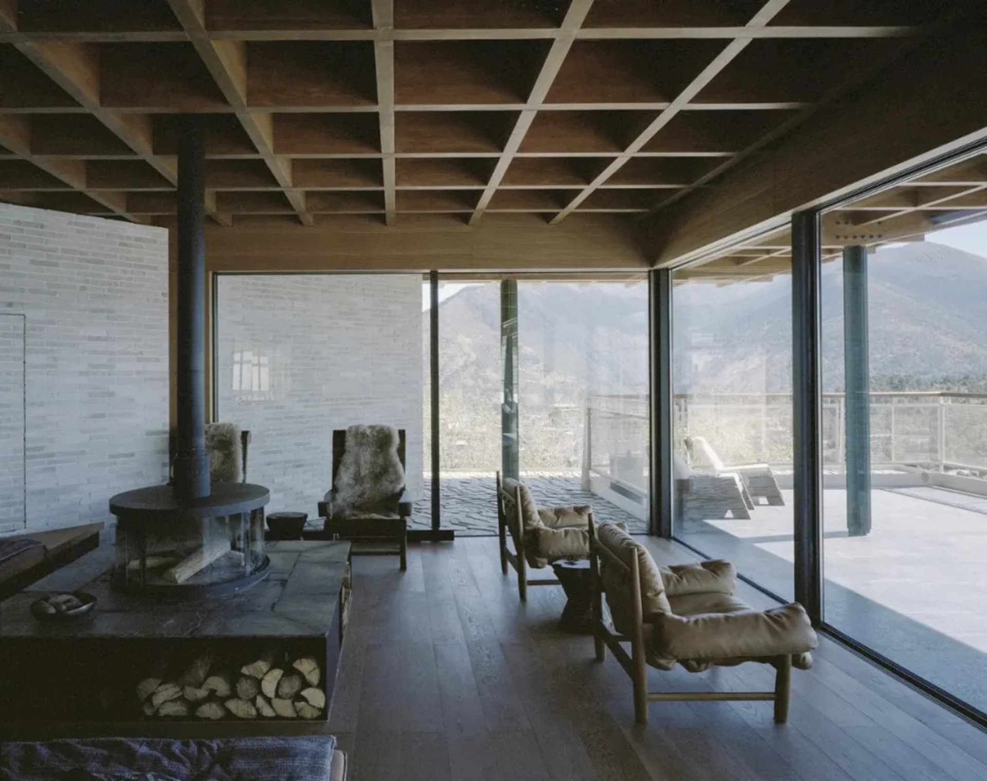 A well-lit living room with a wooden floor, a fireplace, a couch, and a chair, creating a warm and inviting atmosphere