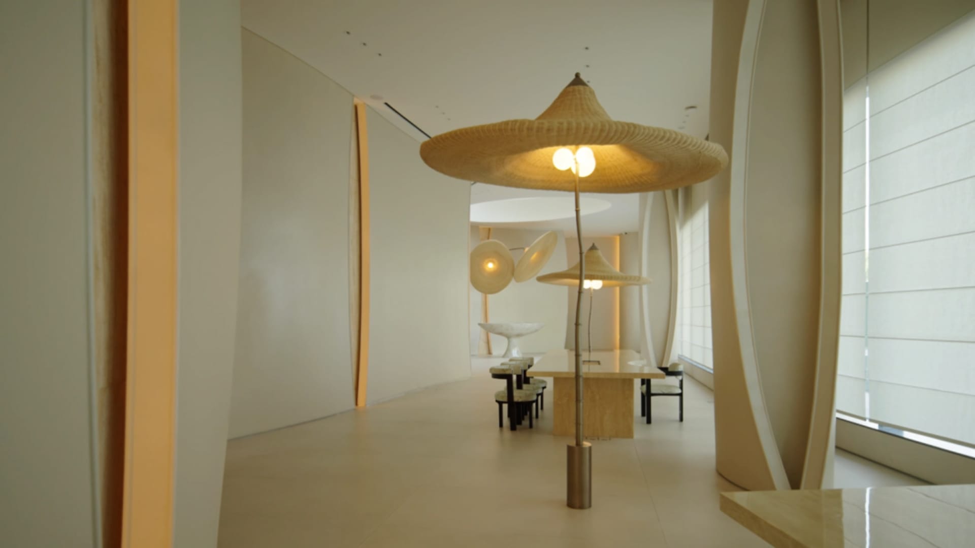 Large, empty dining room with a white color scheme, a dining table, and chairs, illuminated by natural light