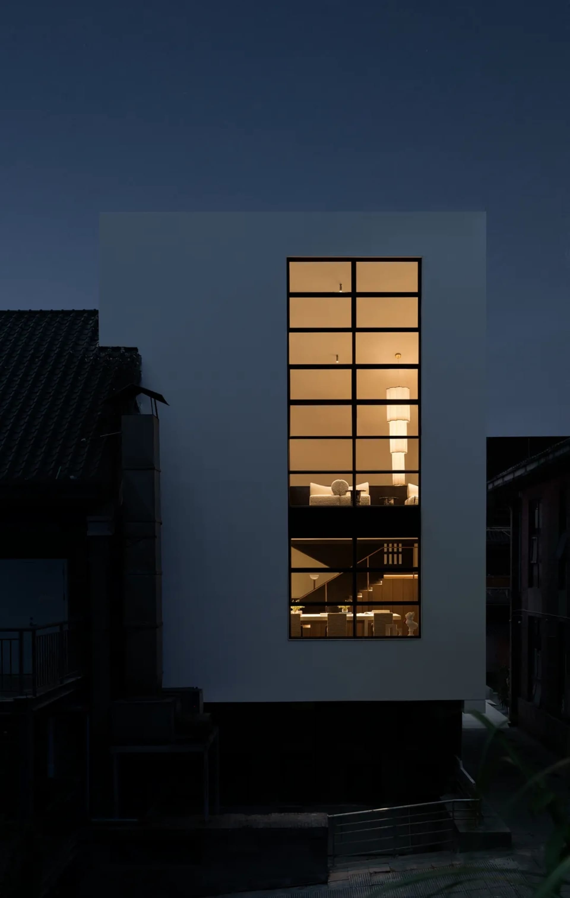 A large white house with a modern design, featuring a large glass window and a bright, inviting interior with clean lines and minimalistic aesthetics