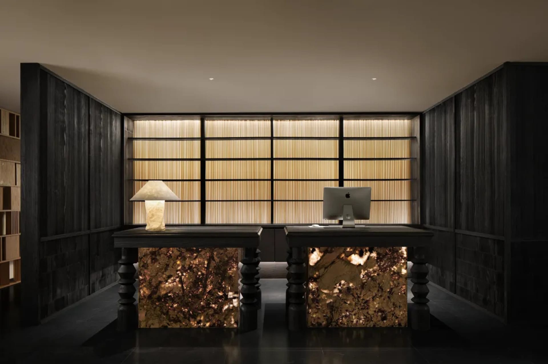 Modern office space with a wooden desk, marble top, and natural light from a large window
