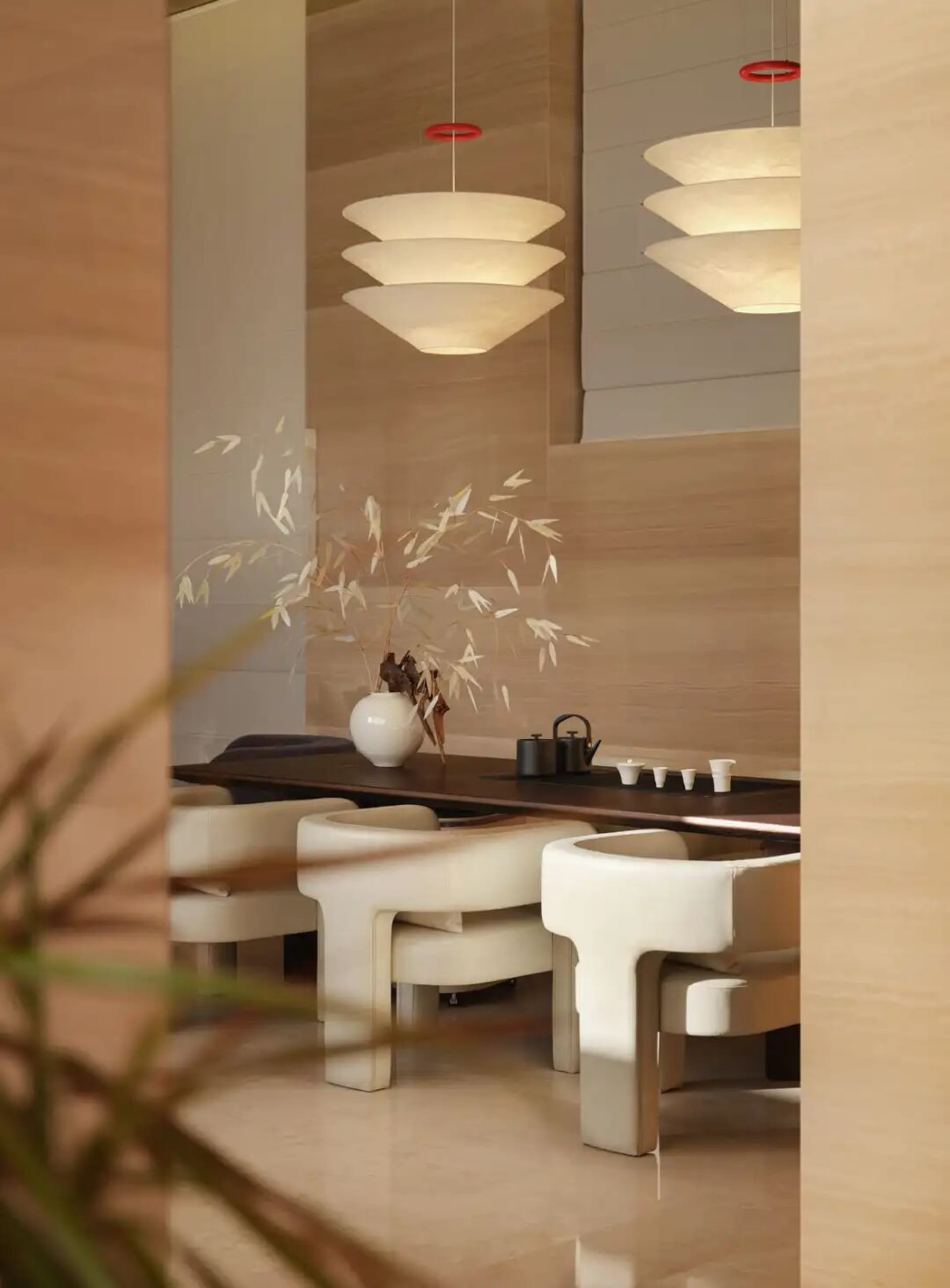 一間燈光明亮的餐廳，內有木質餐桌和餐椅，周圍擺放花瓶，呈現現代優雅的氛圍