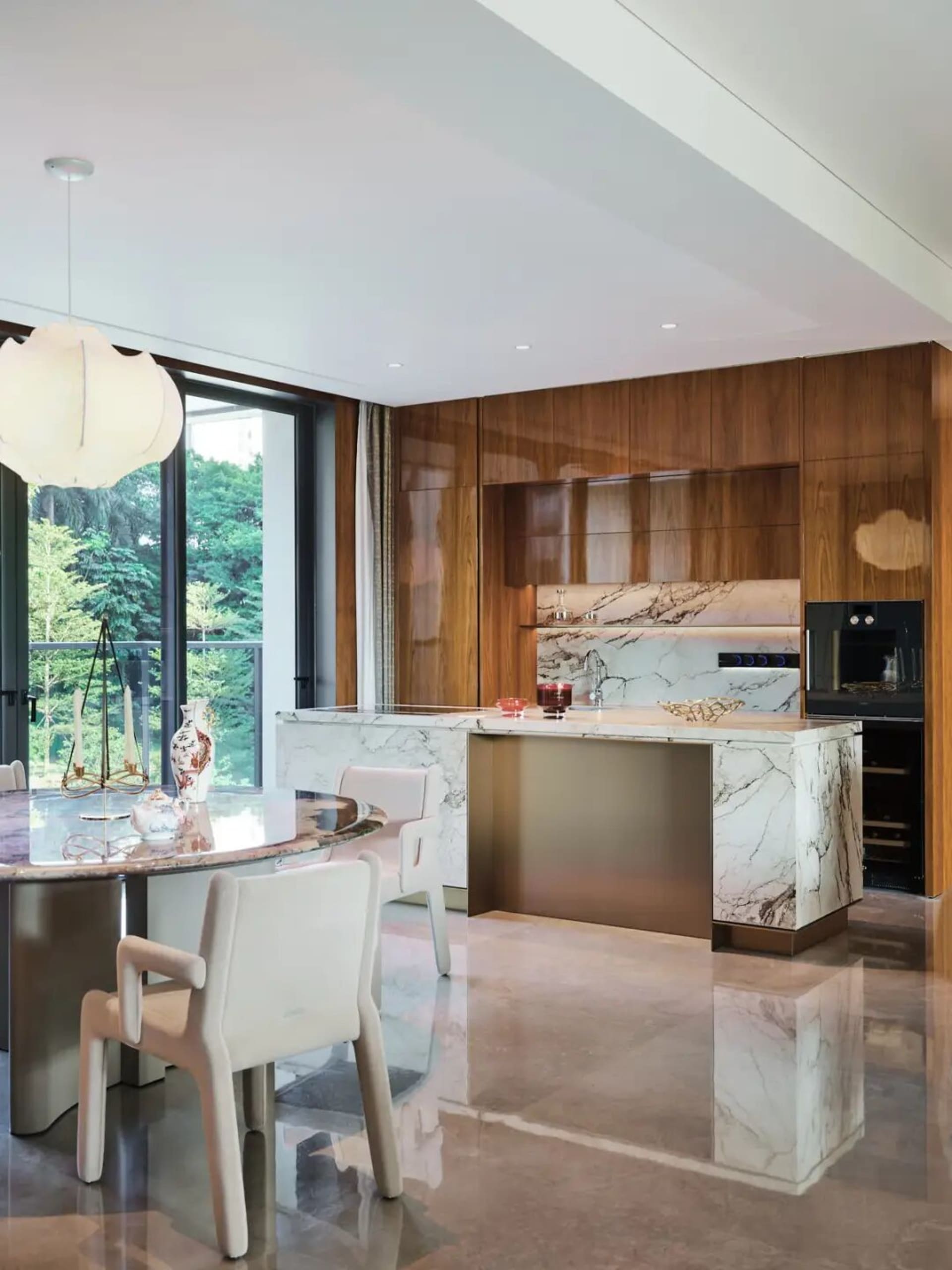 Modern kitchen and dining area with a large island, marble countertop, and comfortable seating arrangement, decorated with a vase and potted plant